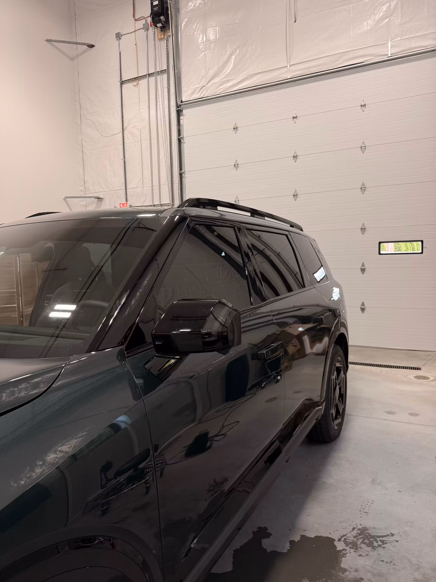 Finished dark window tint on the side and rear glass of an SUV parked inside a clean shop bay.