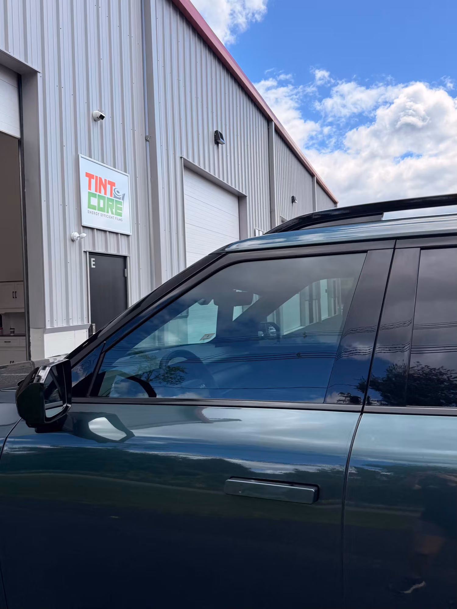 Completed dark tint on the front and rear door windows of an SUV photographed outside the shop.