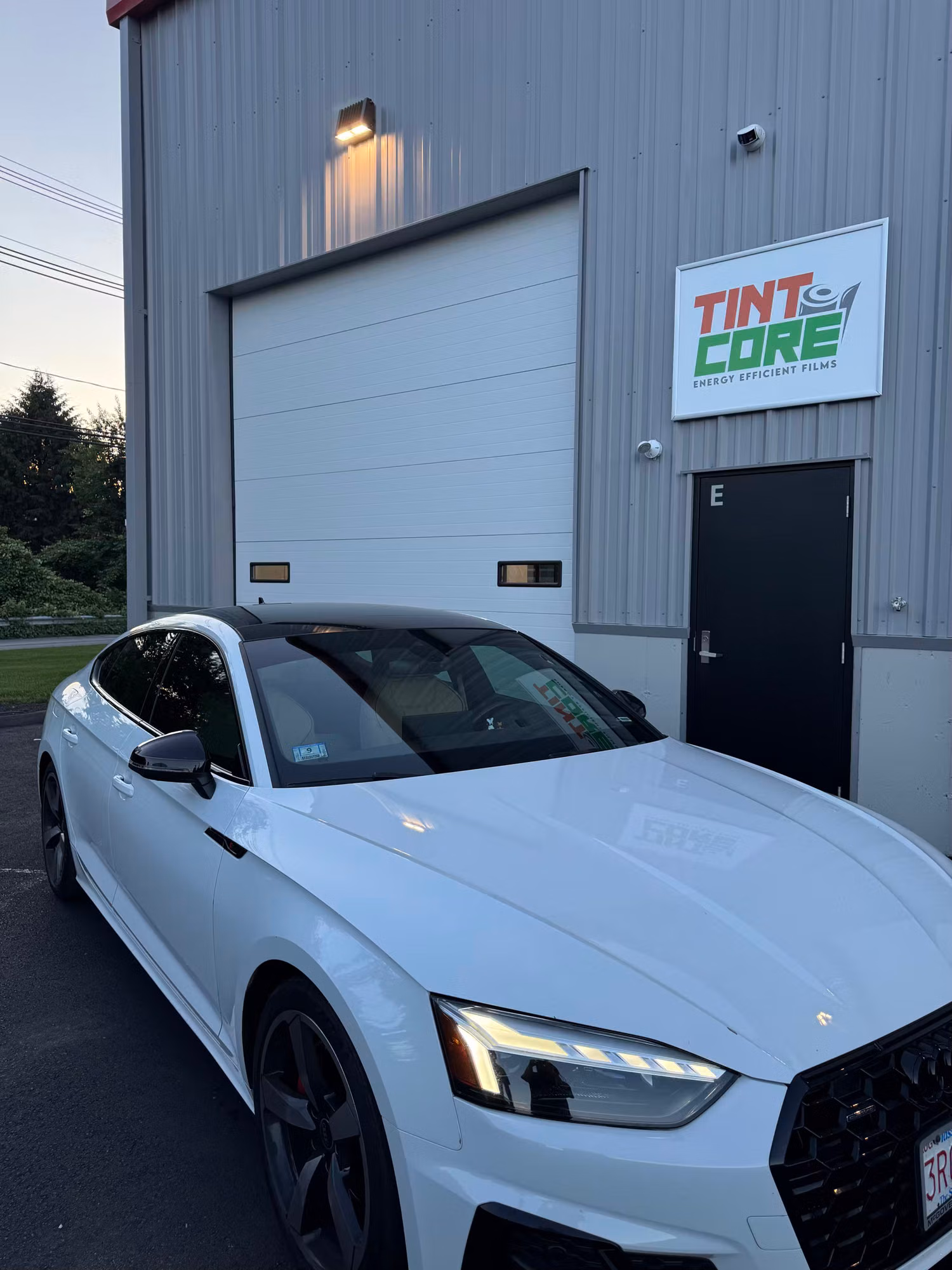 Front three-quarter view of a white sport sedan with dark tinted side glass after installation.