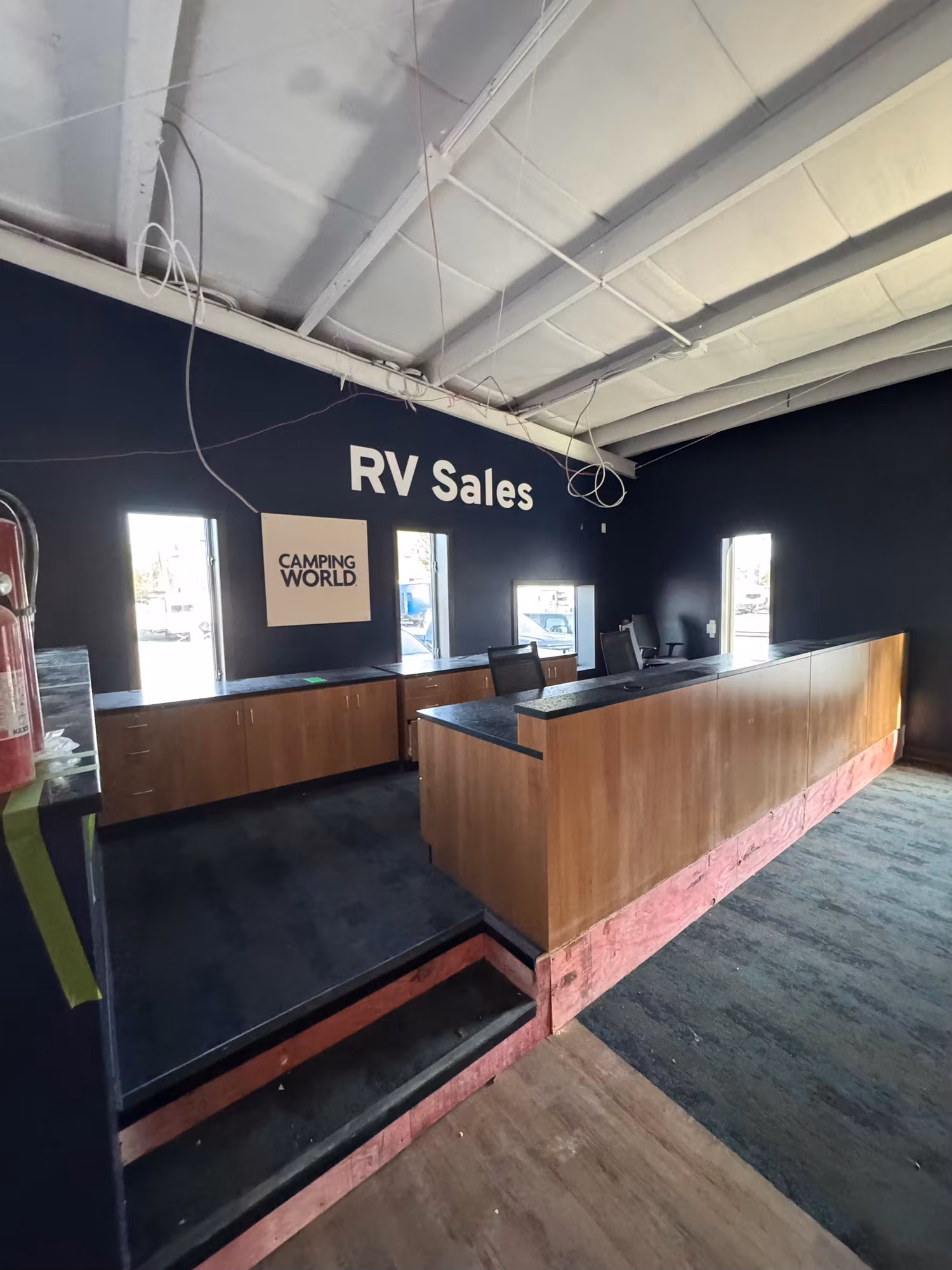 Interior of an RV sales showroom with two tall narrow windows behind a wooden sales counter.