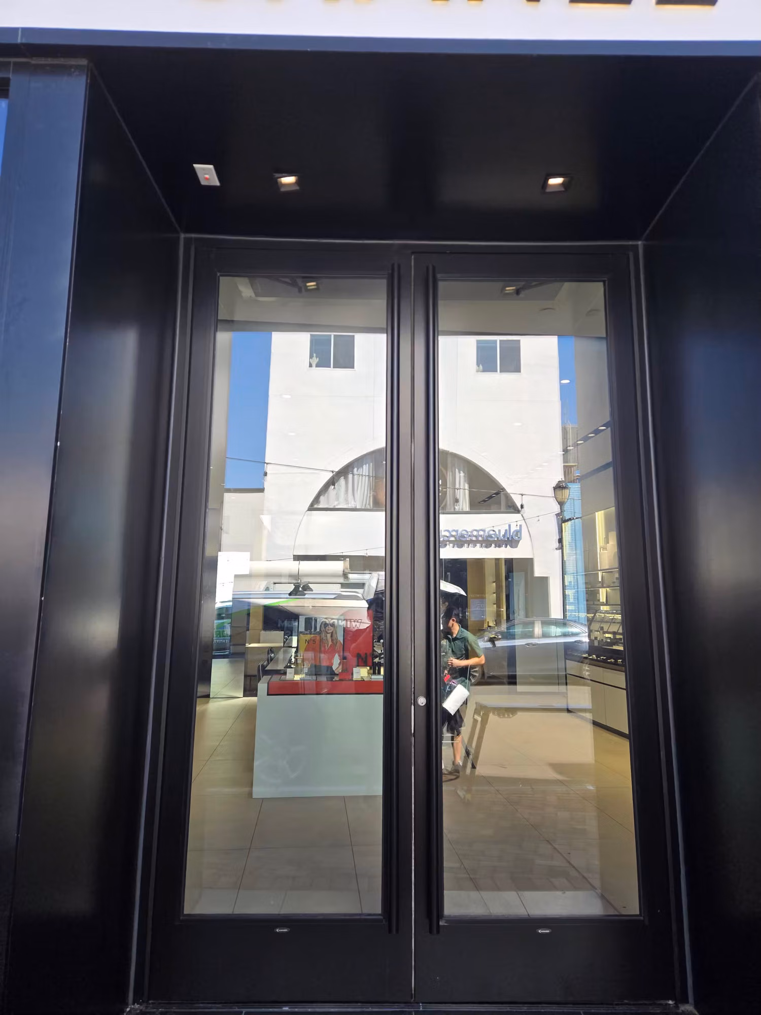Double black-framed glass entry doors on a retail storefront fitted with clear protective window film.
