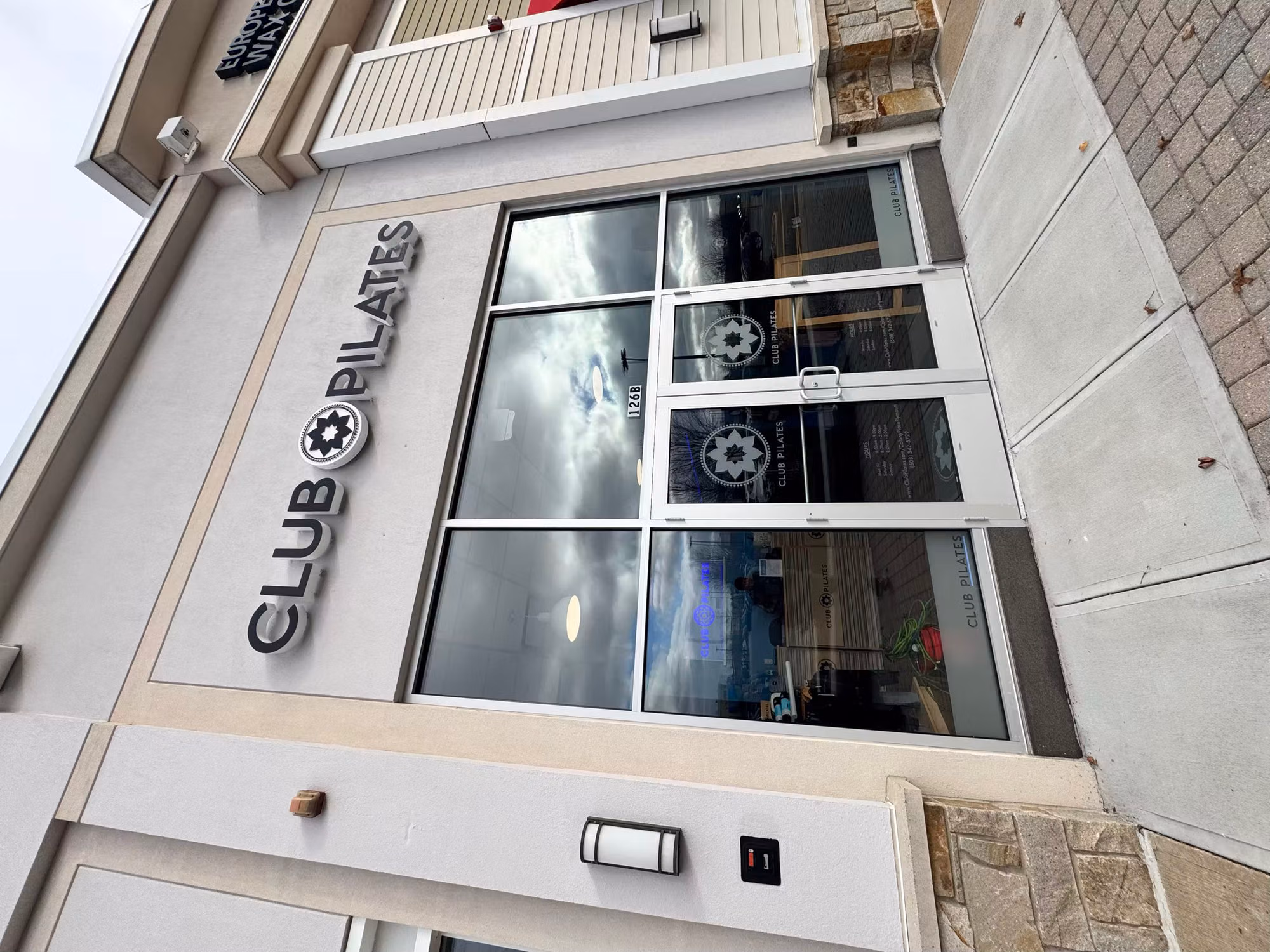 Commercial fitness studio storefront with darkened, reflective glass windows and glass entry doors treated with window film.