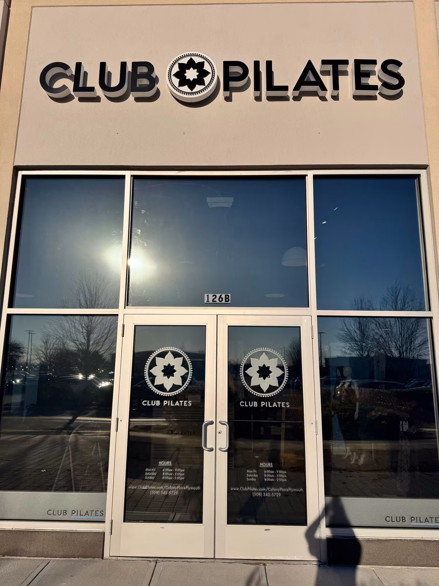 Glass entry doors and sidelights with cut vinyl logo graphics beneath a storefront sign.