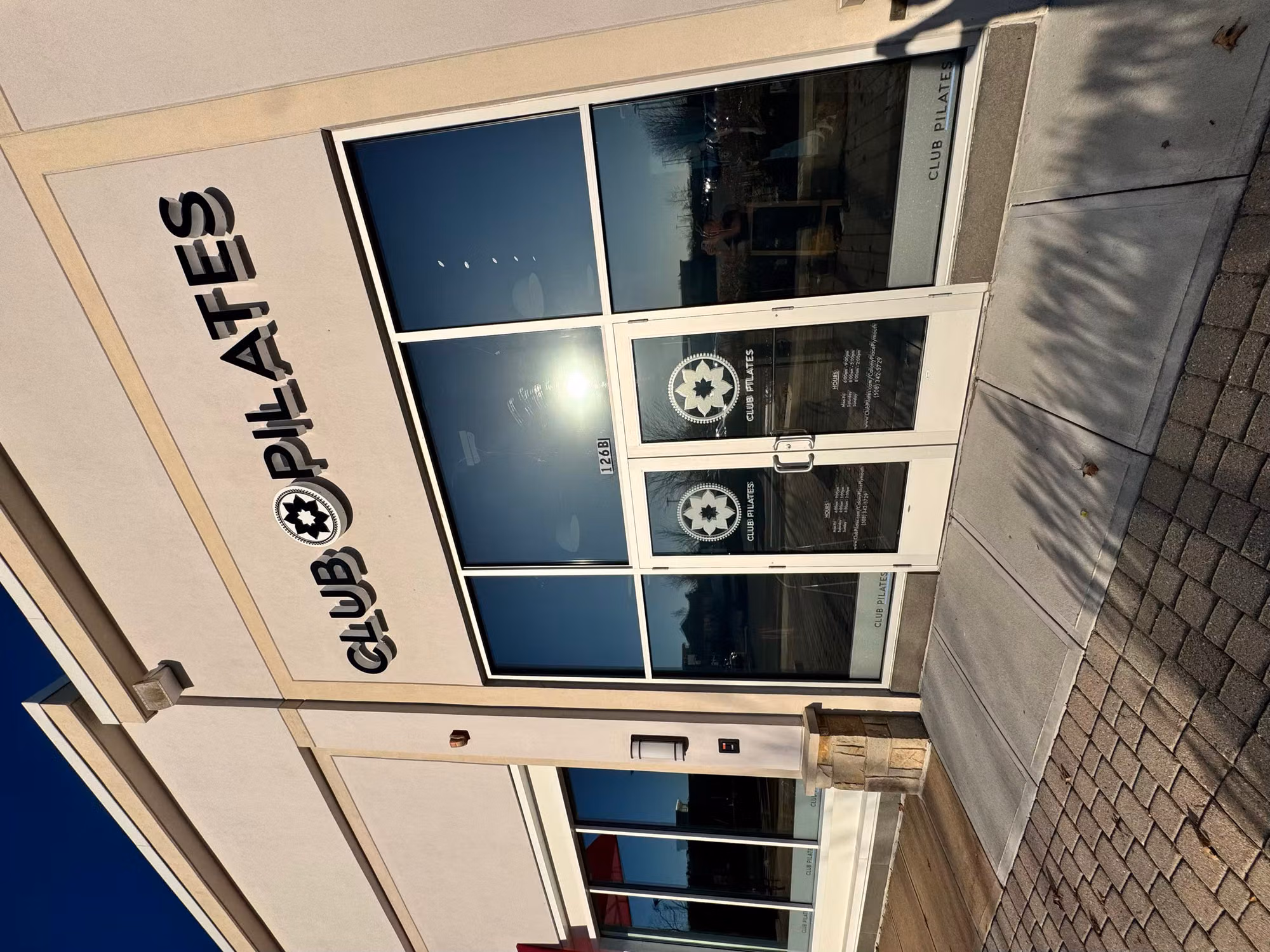 Angled exterior view of glass entry doors with logo decals and tinted storefront windows along a commercial unit.
