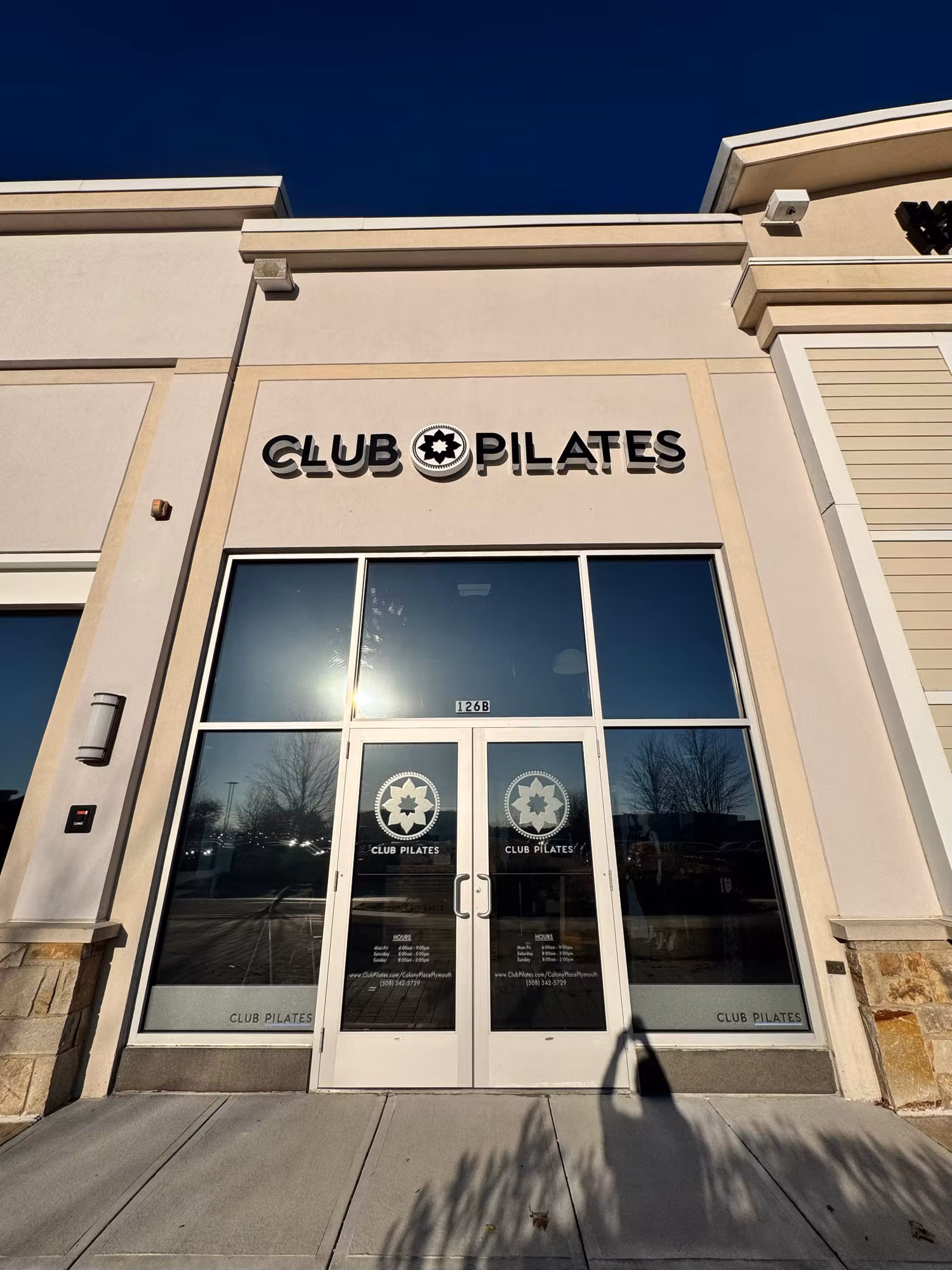 Glass entry doors with sidelights and cut vinyl logo graphics on a commercial storefront against a clear sky.