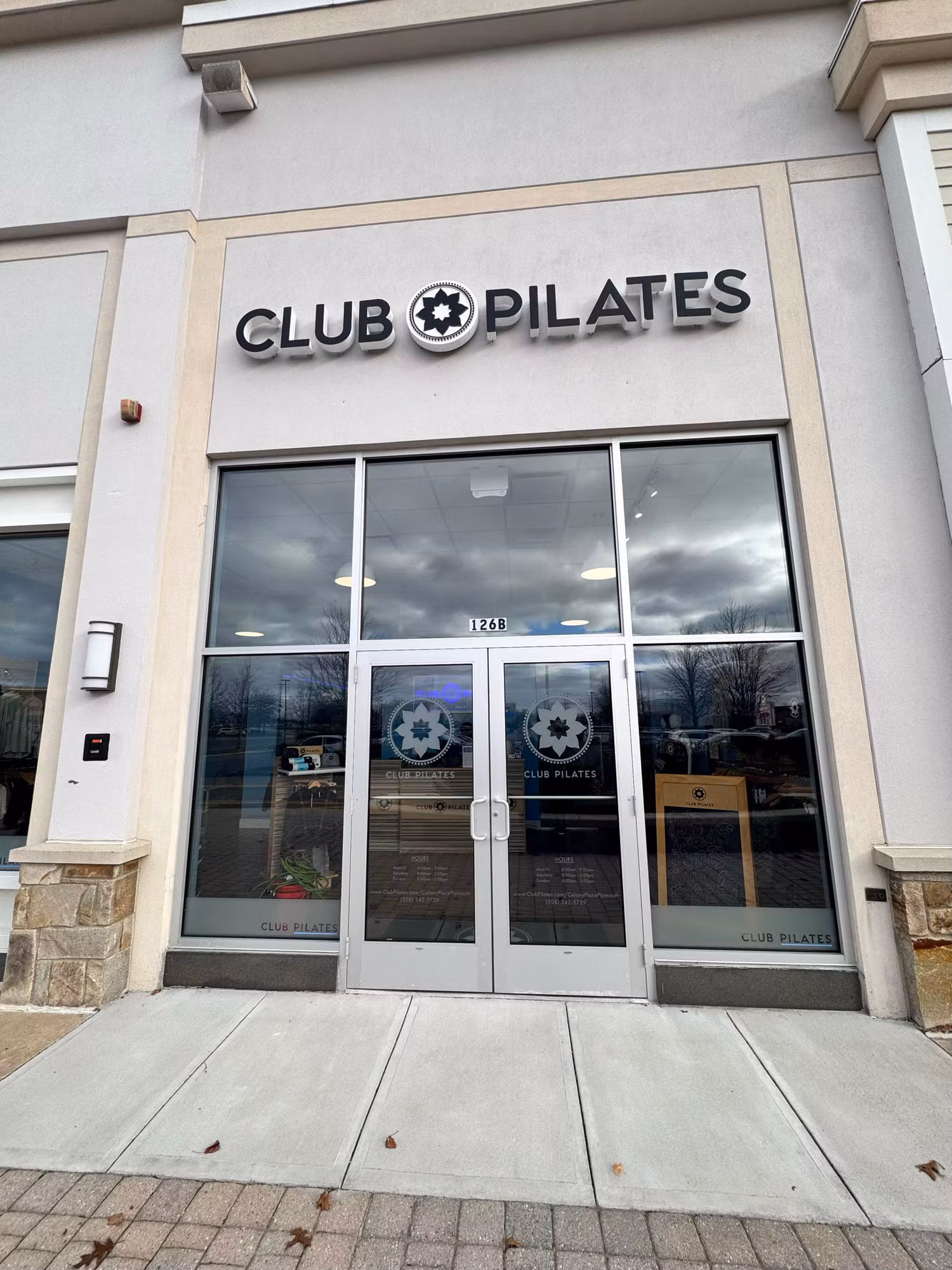 Glass storefront entry doors with frosted circular logo graphics below an illuminated studio sign.