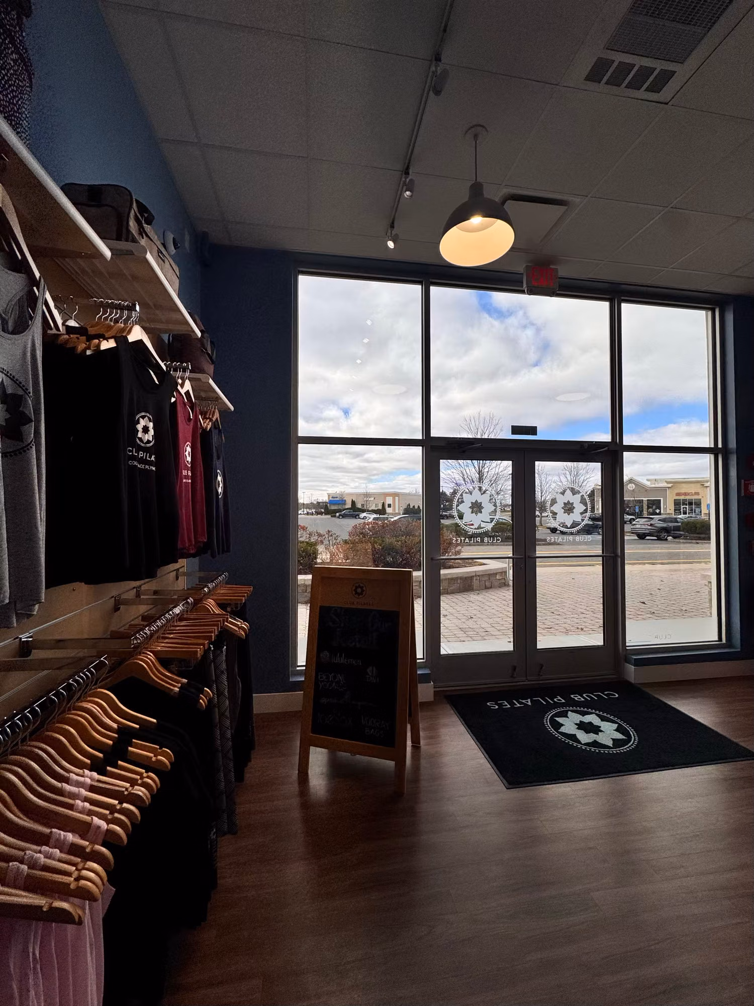 Studio interior with retail displays beside floor-to-ceiling storefront glass carrying frosted emblem and entry-door graphics.
