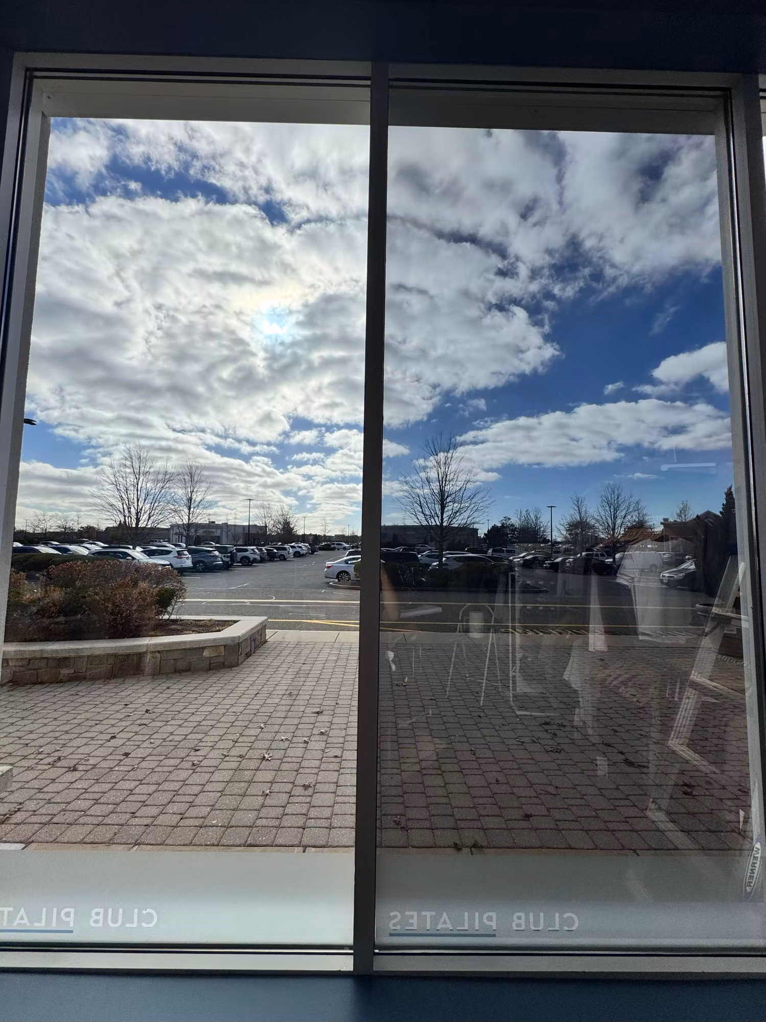 Interior view through a large floor-to-ceiling storefront window with solar control film looking out to a parking lot.