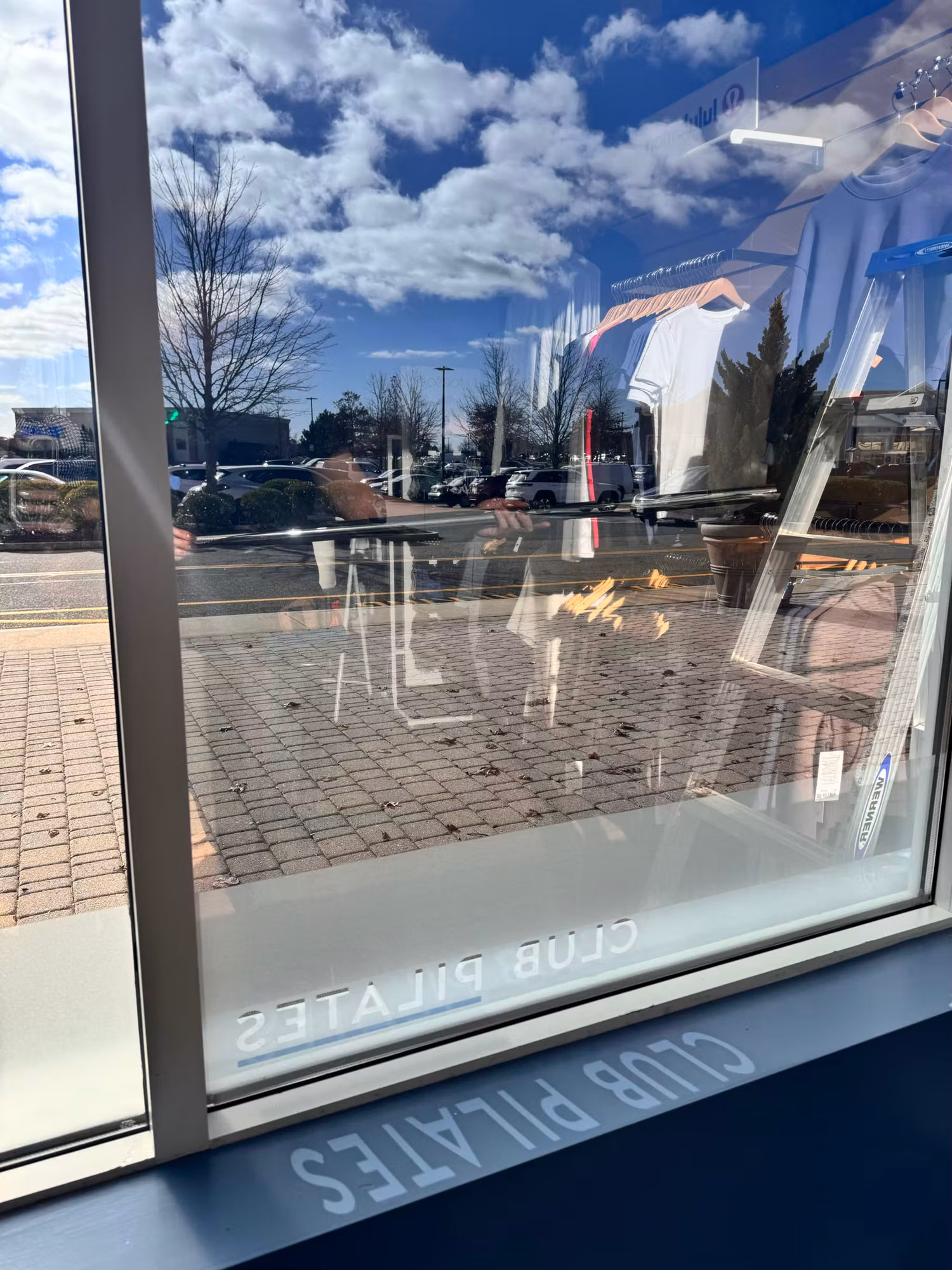 Interior view through a large storefront window with solar control film and a reverse-reading logo decal at the base.
