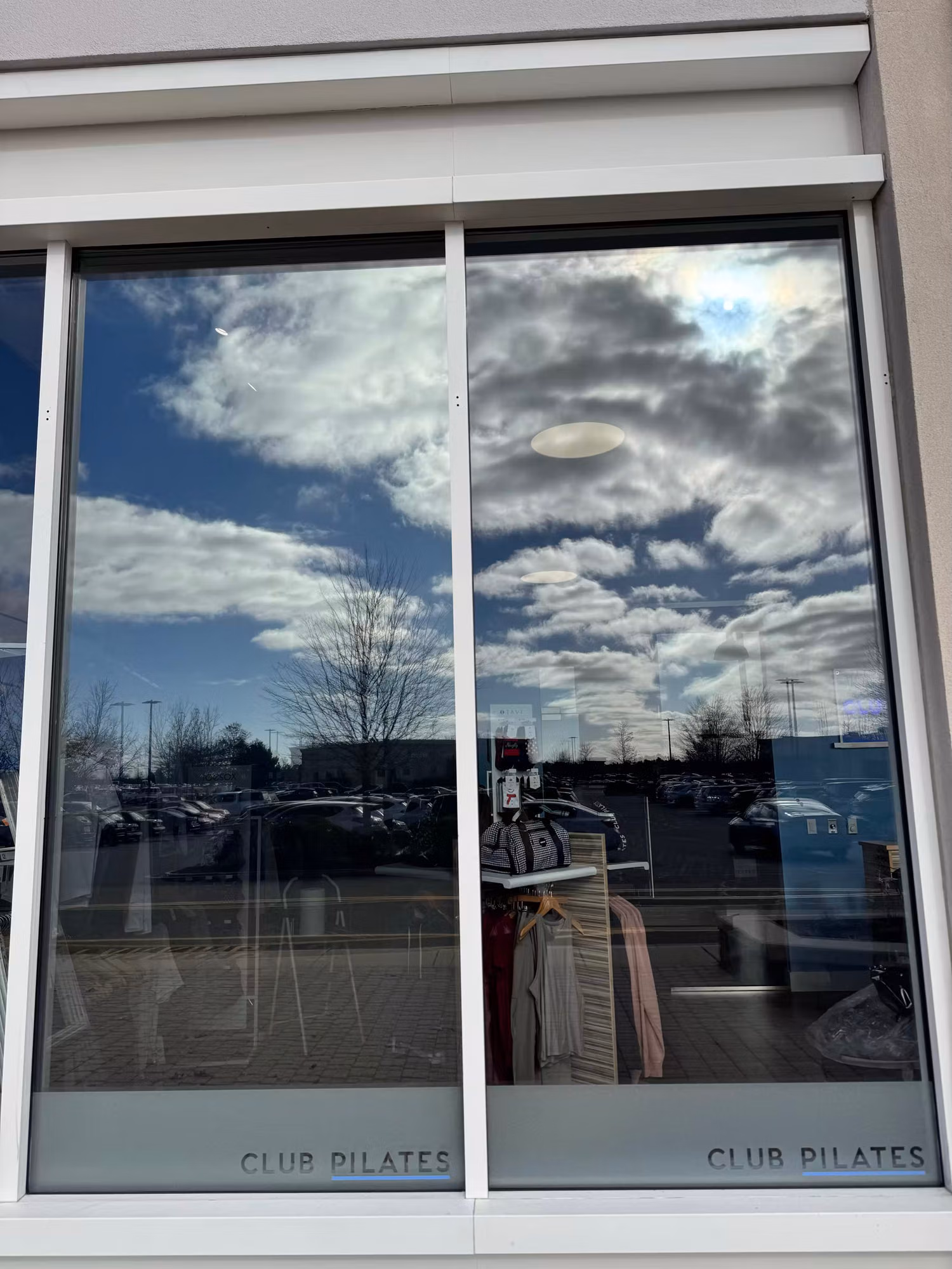 Two-panel storefront window with dark reflective solar film and a frosted lettering band along the bottom.