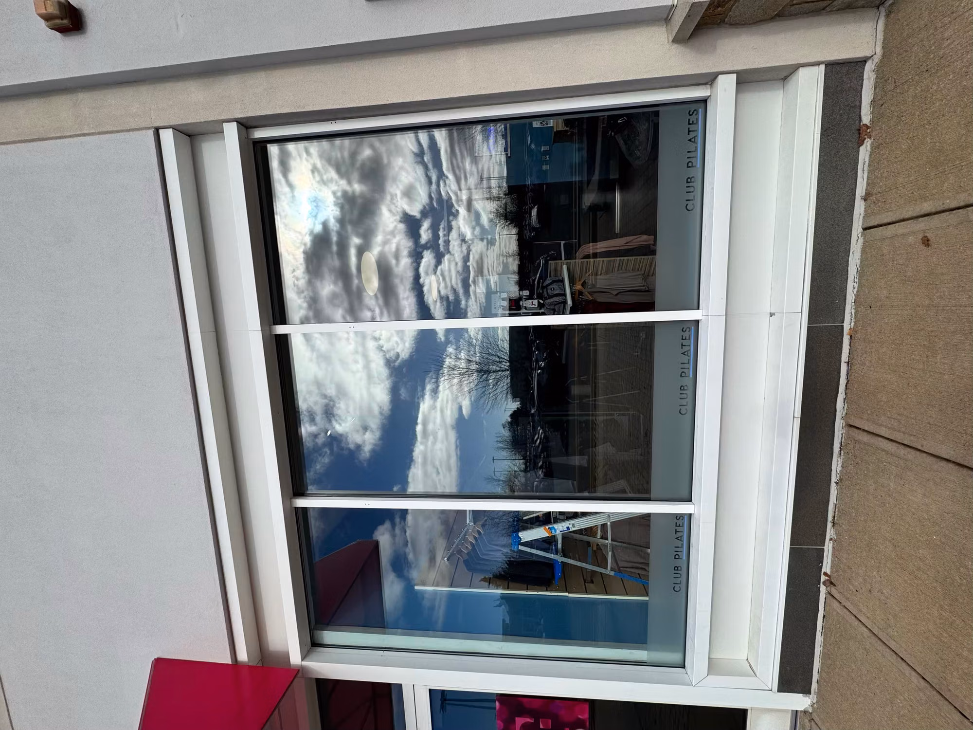 Three-panel storefront picture window with dark reflective solar film and a frosted lettering band.