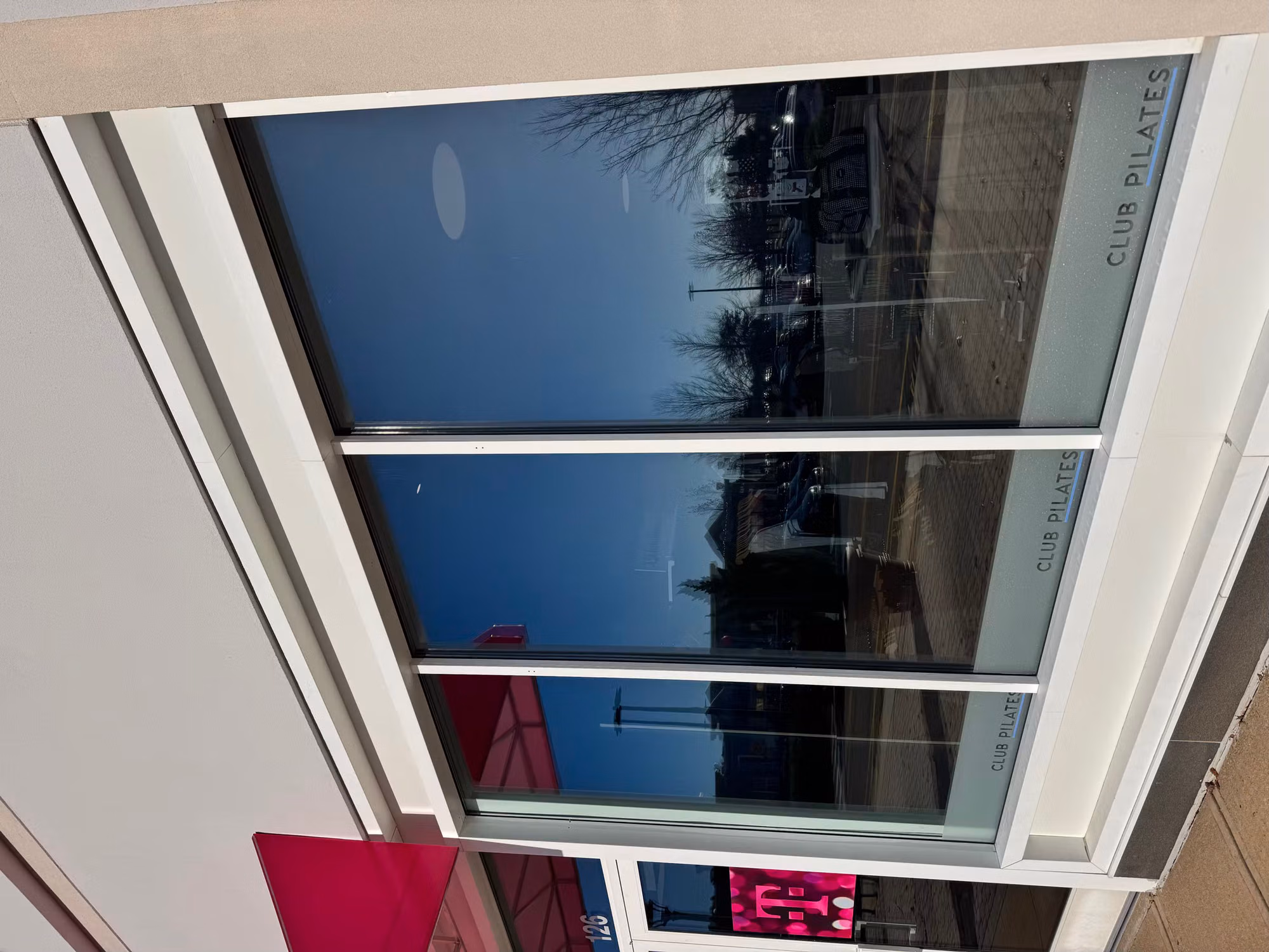 Three-panel storefront window with dark reflective solar film cutting glare from the parking lot.