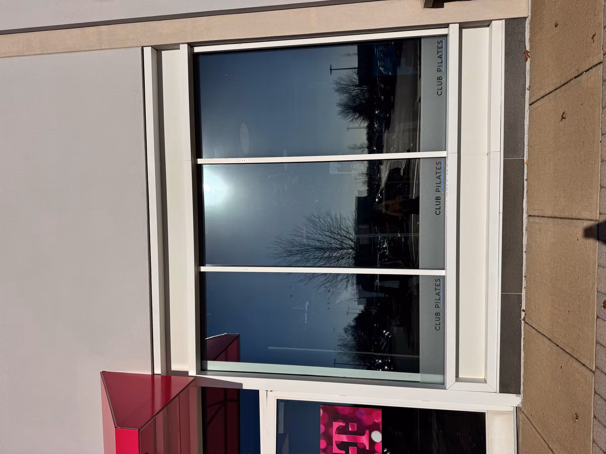 Three-panel storefront window finished with dark reflective solar film along a retail facade.