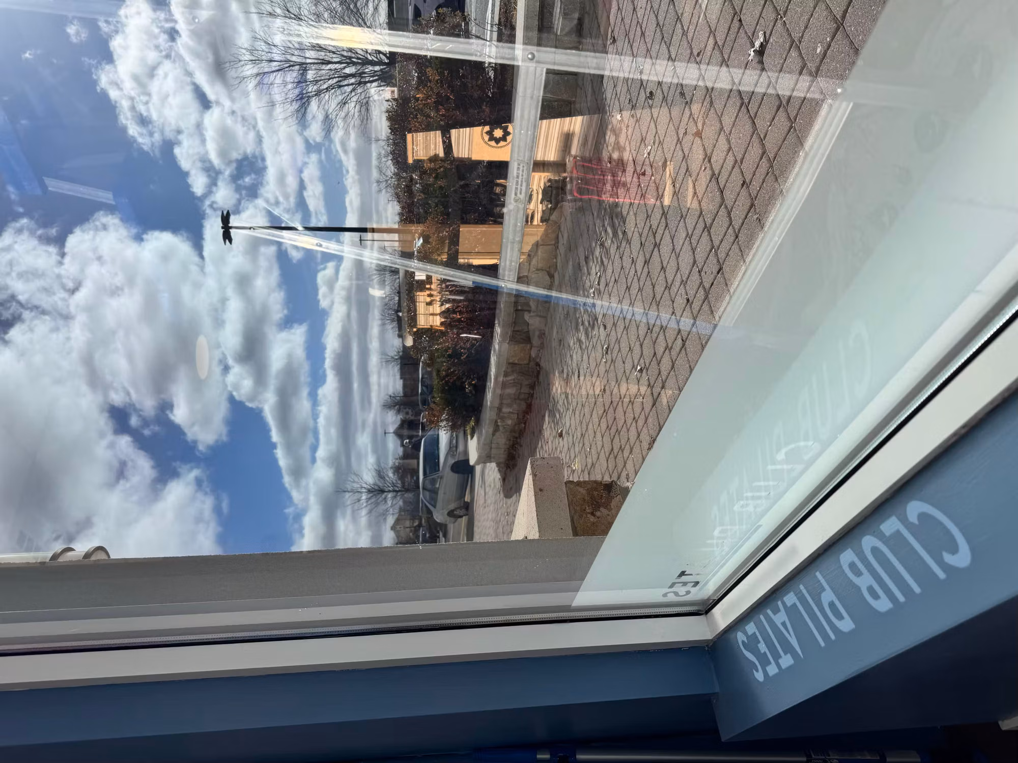 Close view of frosted etched lettering applied along the lower edge of a clear storefront window at a studio.