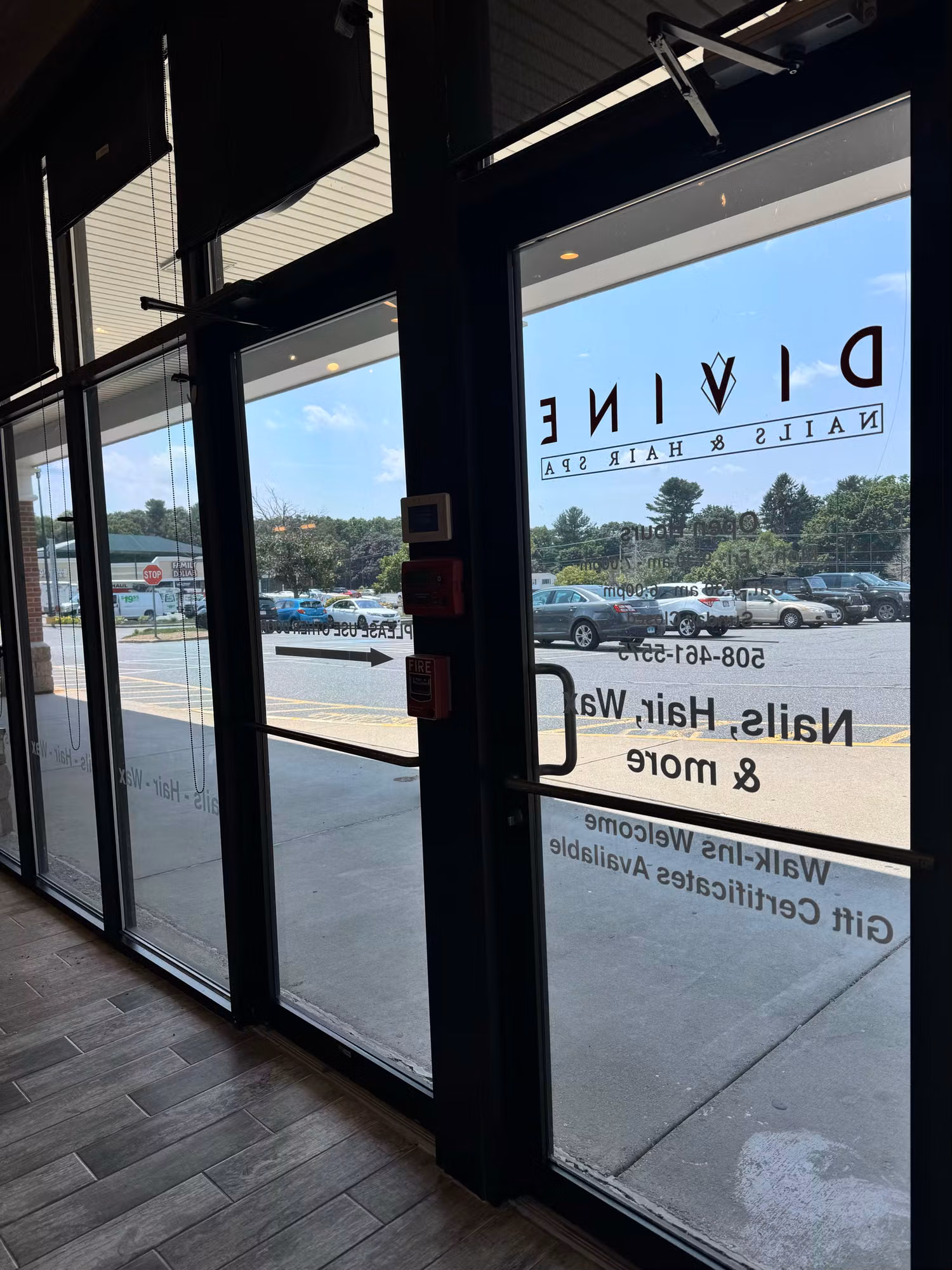 Interior view through a glass entry door showing reverse-reading vinyl salon logo and service lettering on the glass.