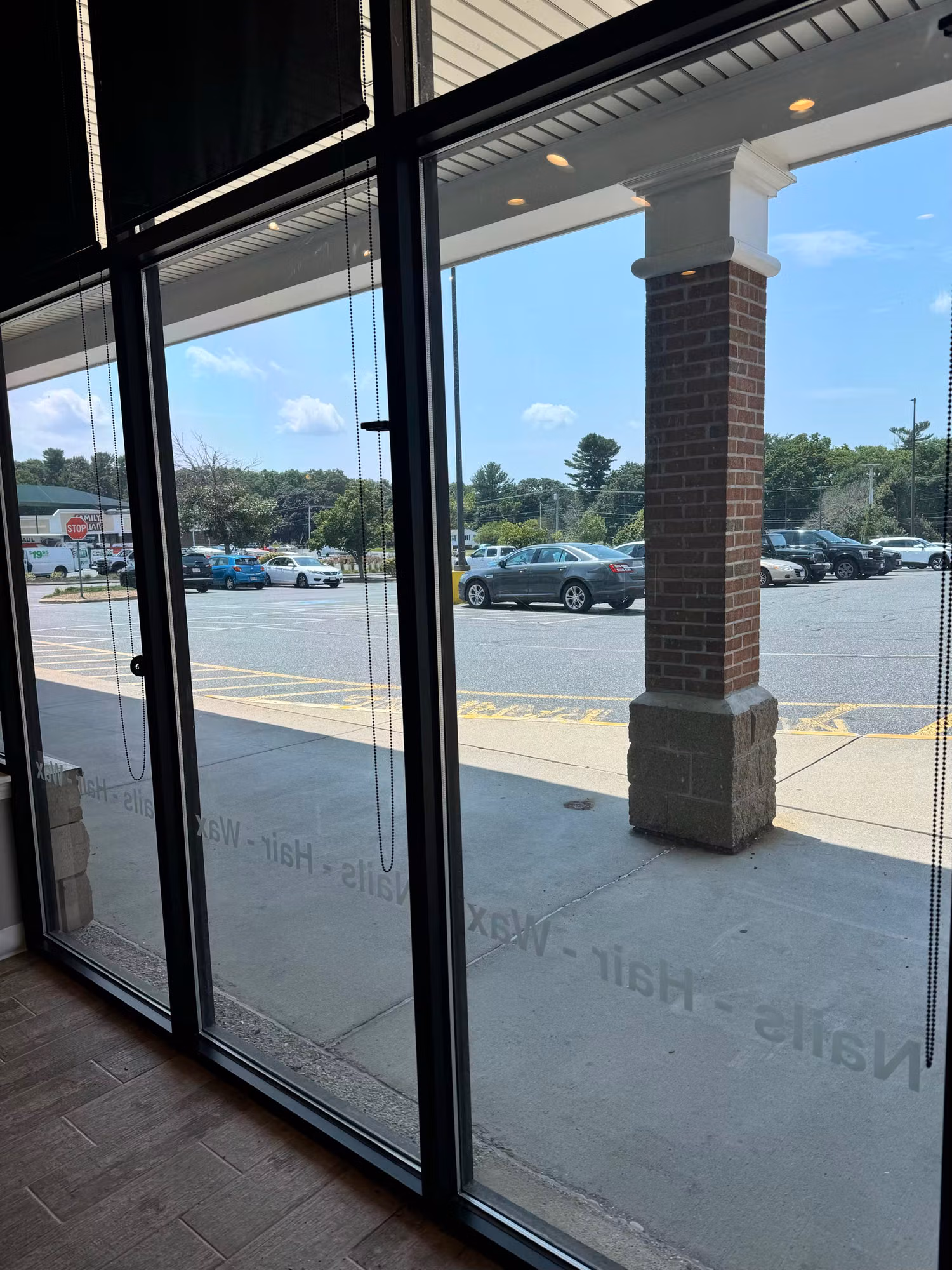 Interior view through floor-to-ceiling storefront glass with reverse vinyl service lettering and a parking lot beyond.
