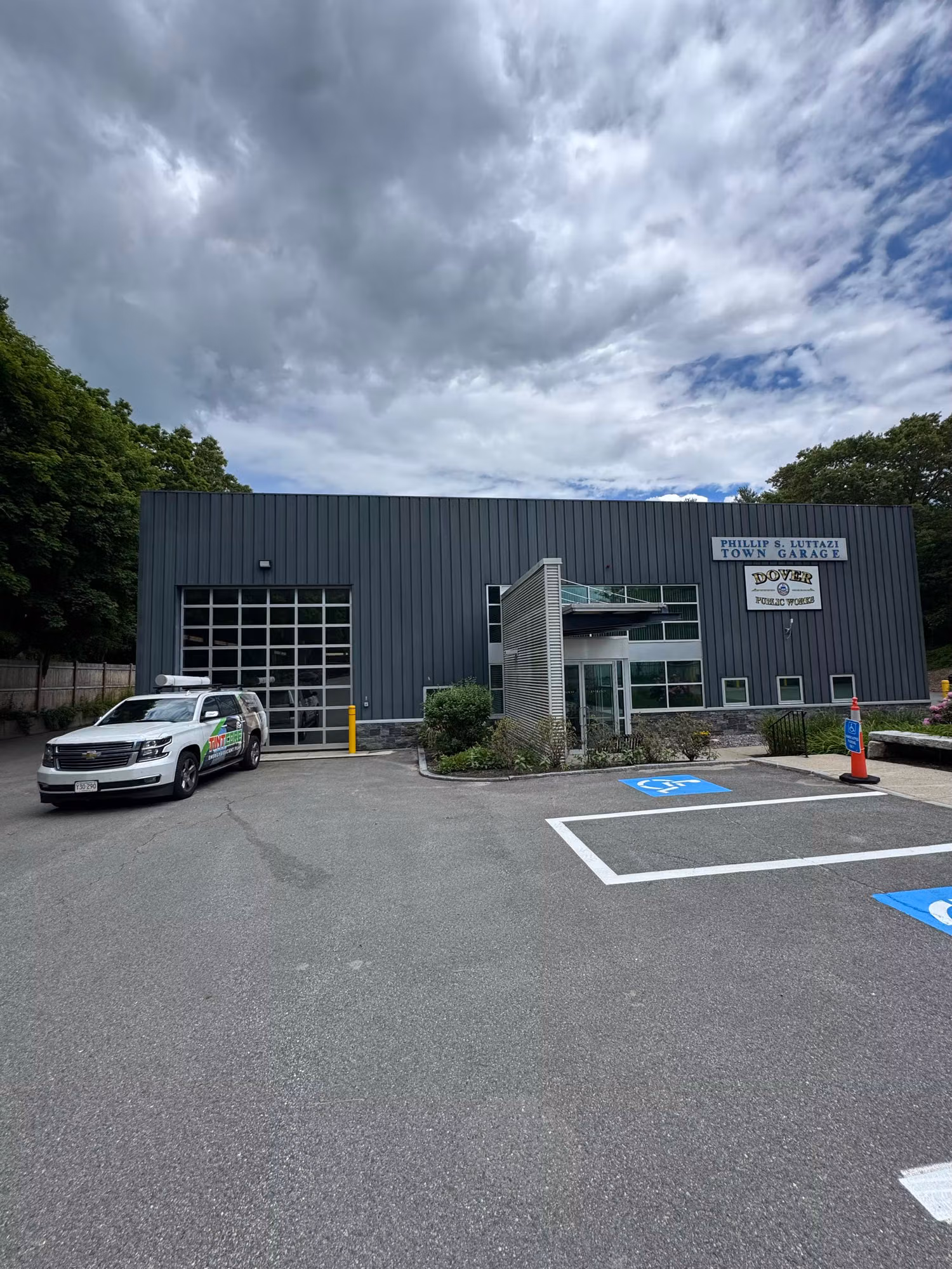 Exterior of a gray metal commercial building featuring a glass overhead door and storefront entry windows.