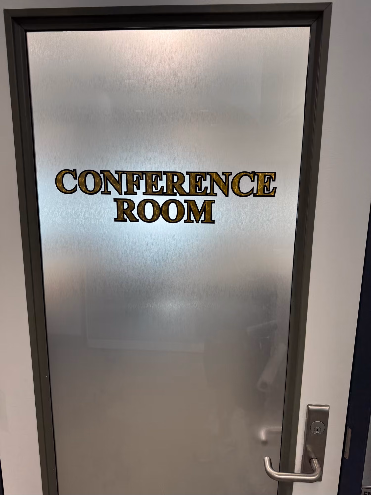 Frosted privacy film on a glass office door with gold Conference Room lettering applied to the front.