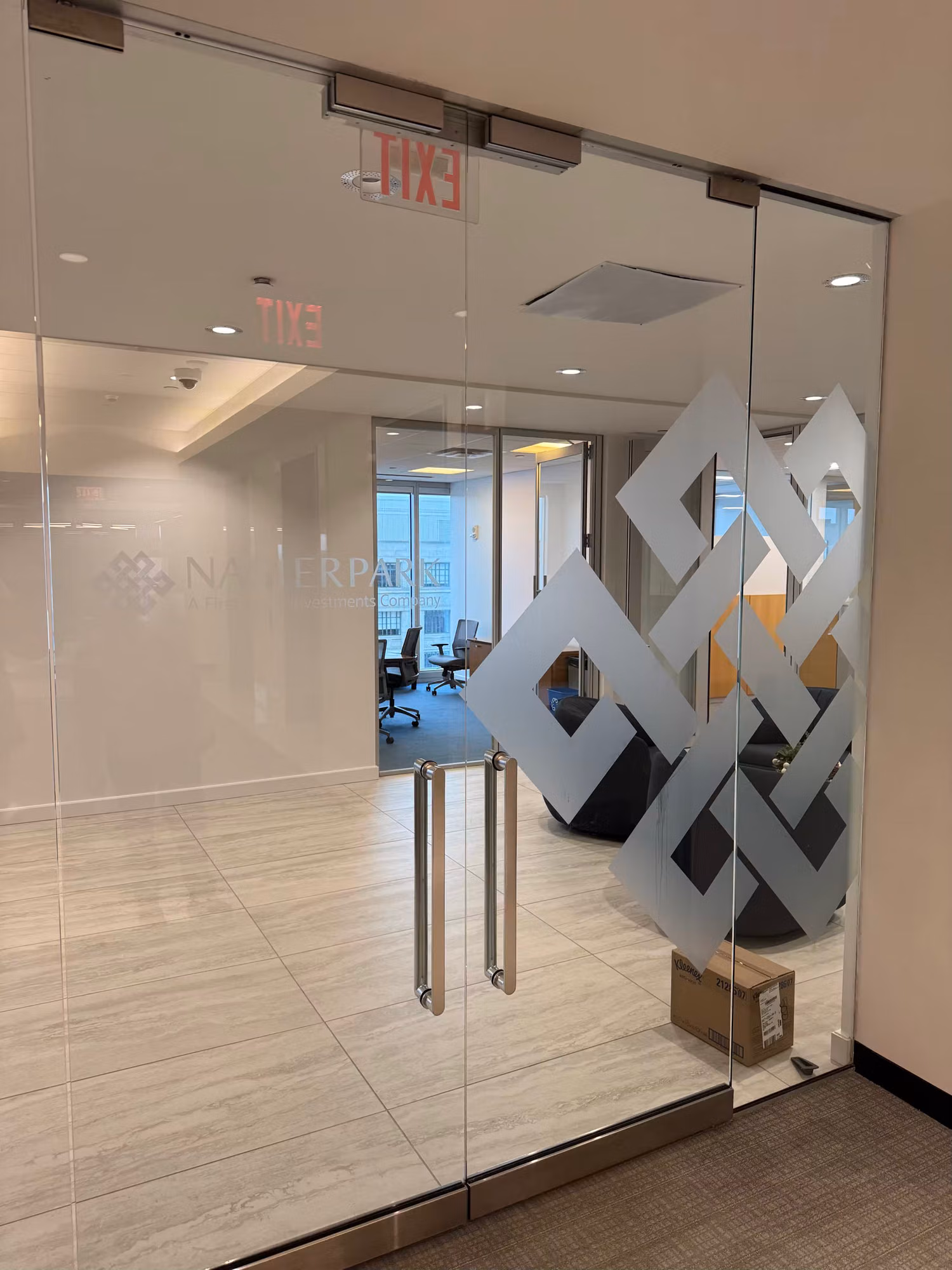 Glass entry doors with a frosted geometric logo graphic and a frosted etched logo on the side partition.