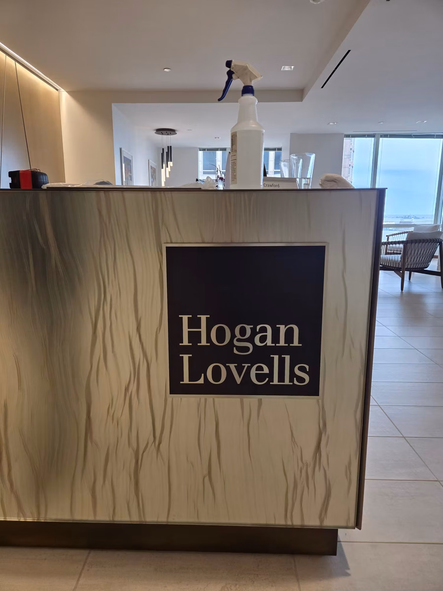 Office lobby reception desk with a branded logo panel and a spray bottle resting on top.