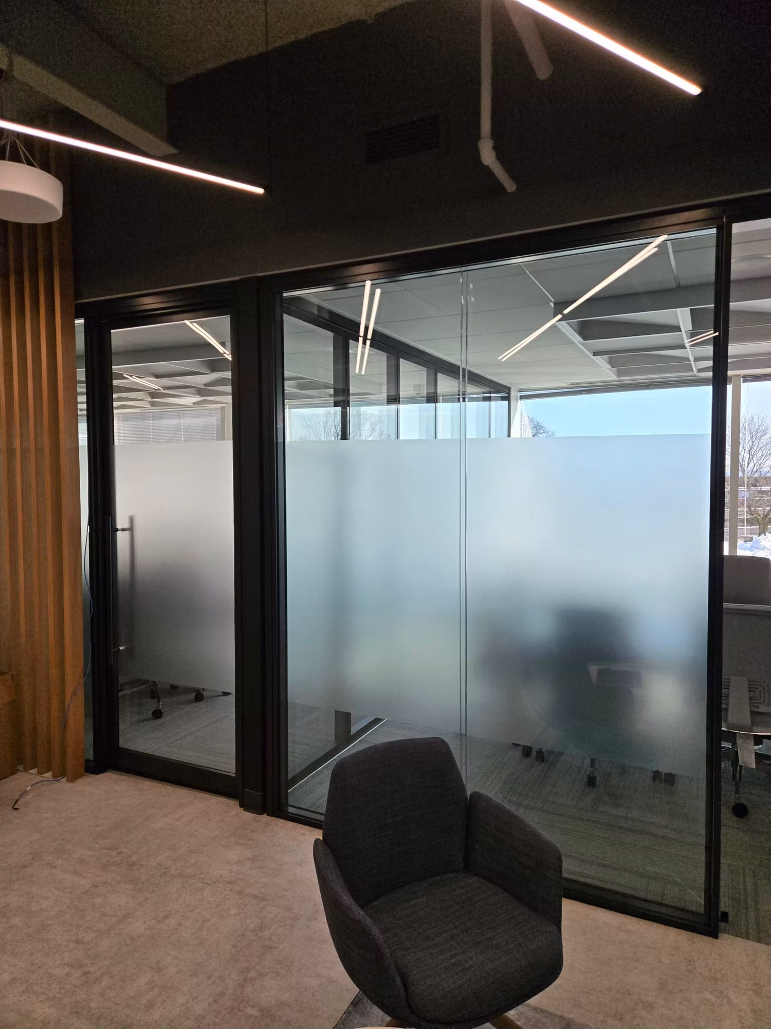 Conference room glass partition wall with a frosted privacy band obscuring the meeting table inside.