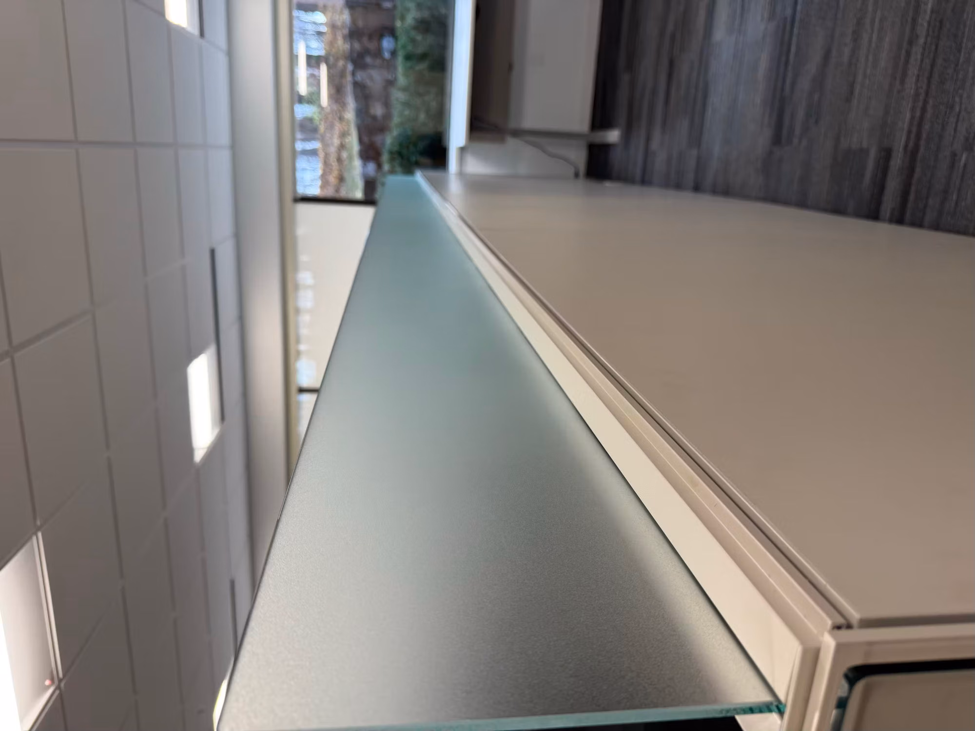 Frosted glass privacy topper running along a cubicle partition in a daylit open office.