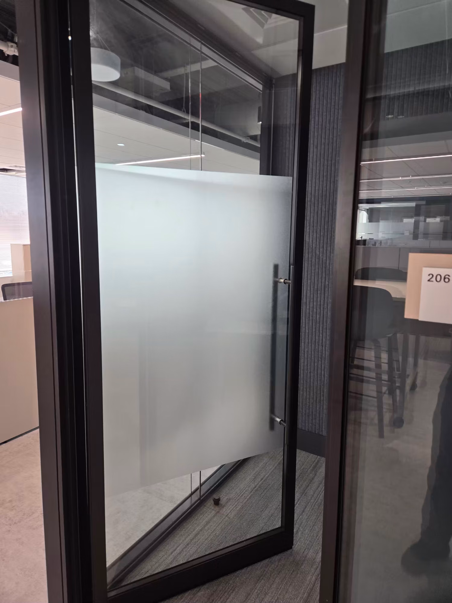 Black-framed glass office door with a frosted privacy film panel centered for screening views inside.
