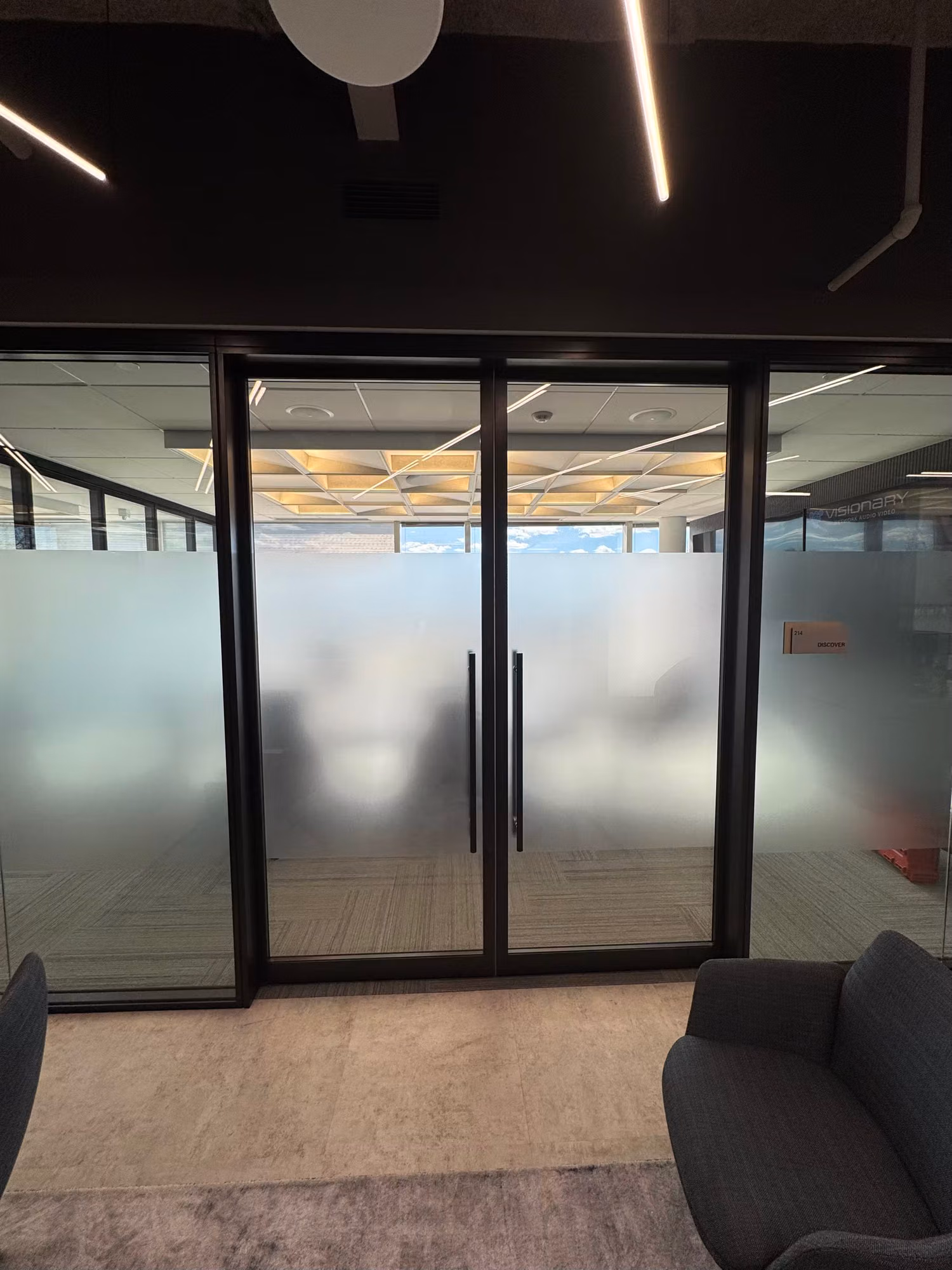 Glass partition wall and double doors with a frosted privacy band screening the office space behind.