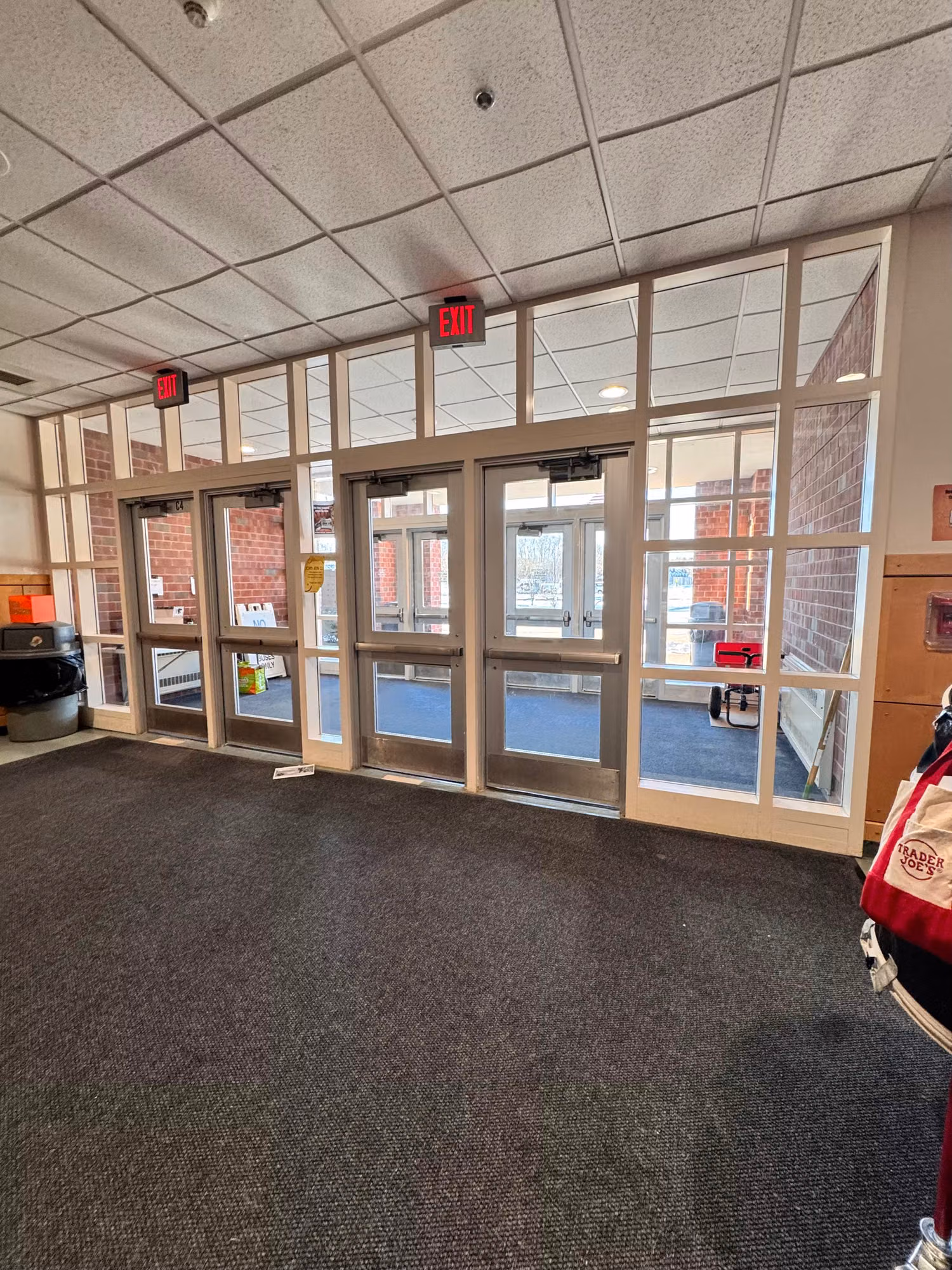 Row of glass entry doors with transom windows in a building vestibule fitted with protective window film.