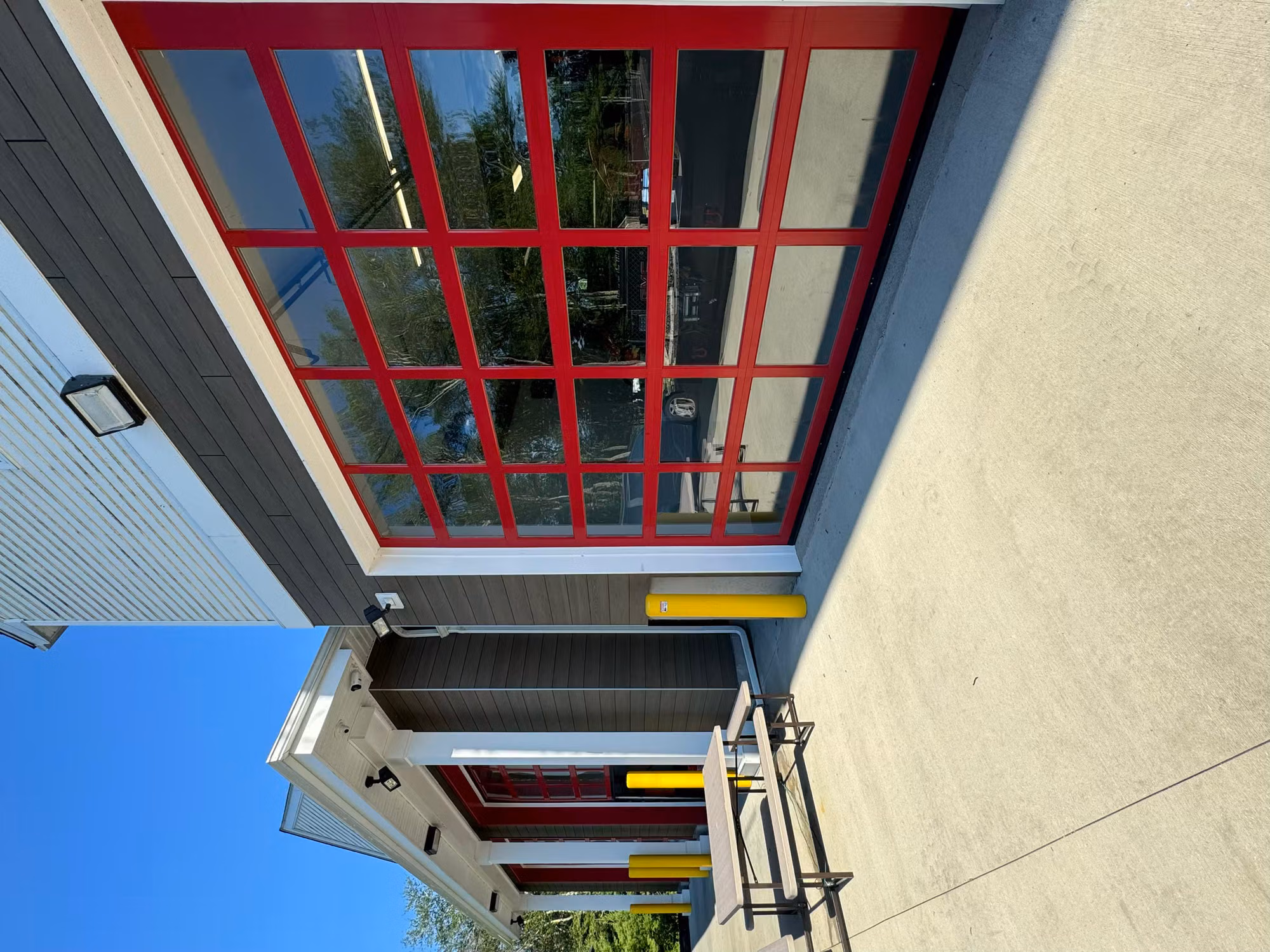 Large red-framed glass bay door on a fire station with darkened solar control film on the panels.