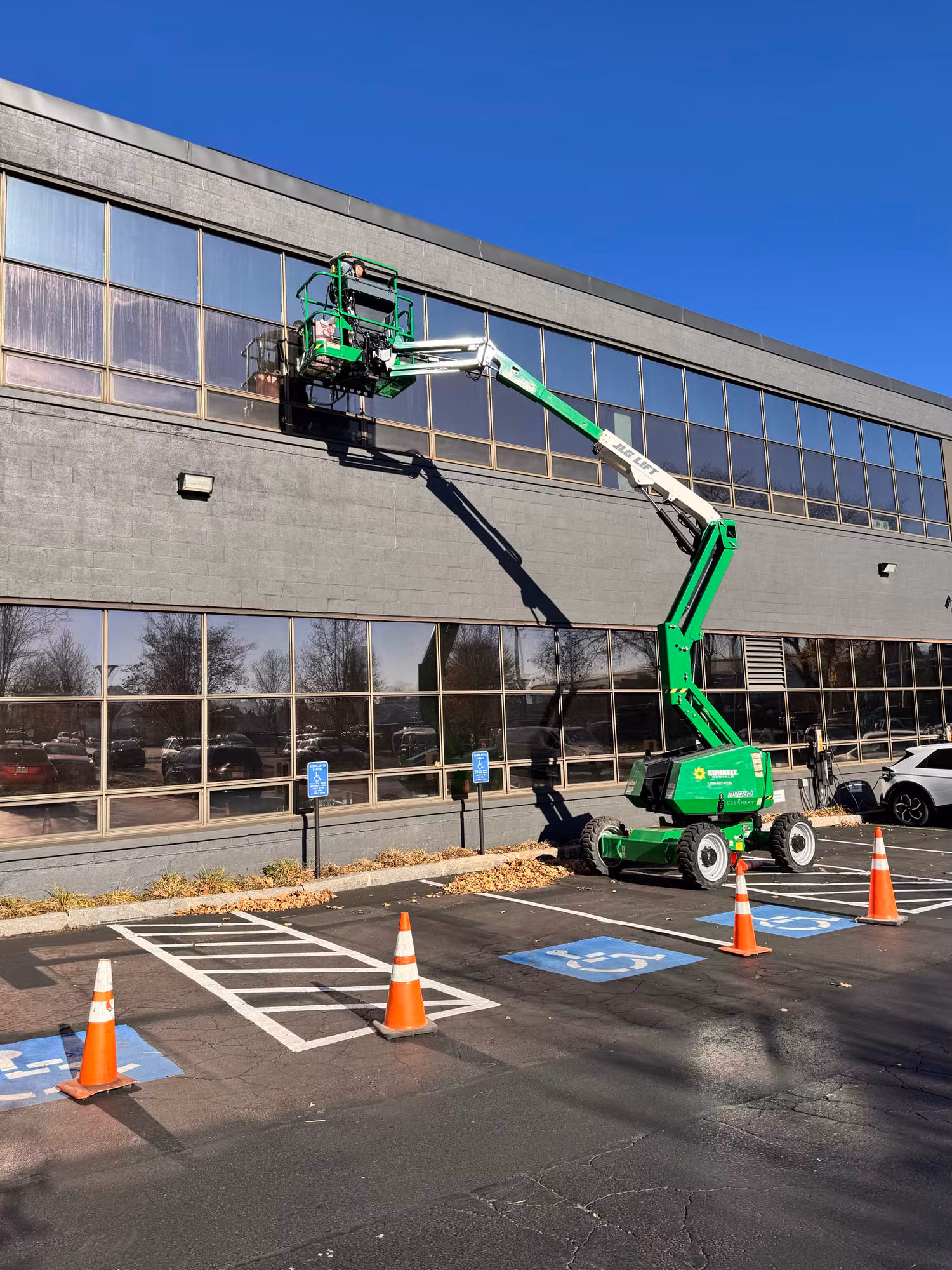 Window film being installed on the upper-level windows of a commercial office building from an articulating boom lift.