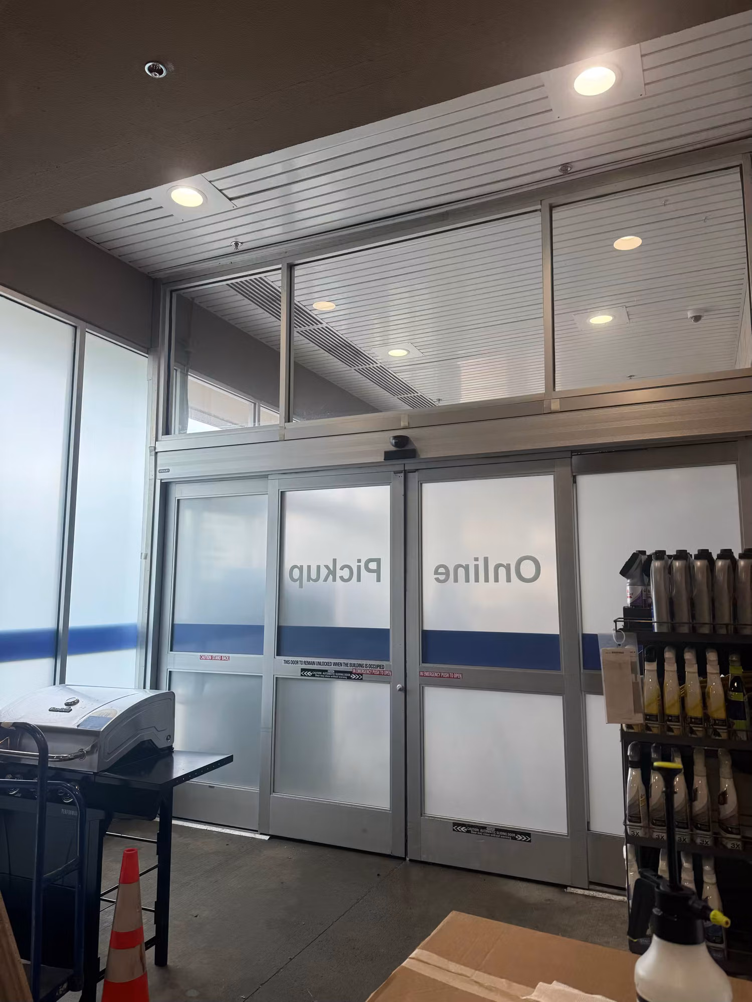 Interior view of automatic sliding entry doors with cut-vinyl Online Pickup lettering and frosted privacy band on the glass.