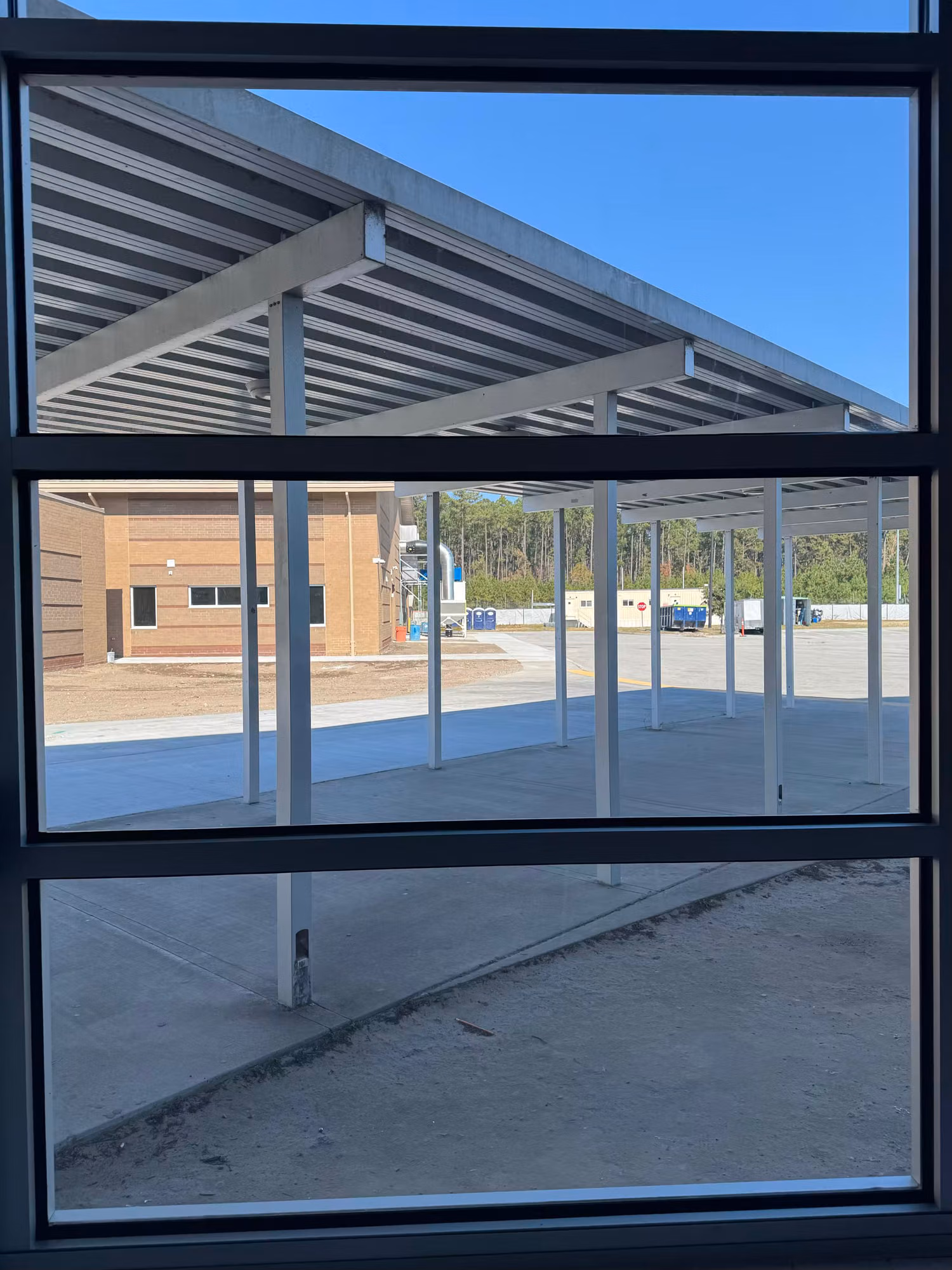 Large tinted commercial window looking out onto a covered courtyard canopy and adjacent building.