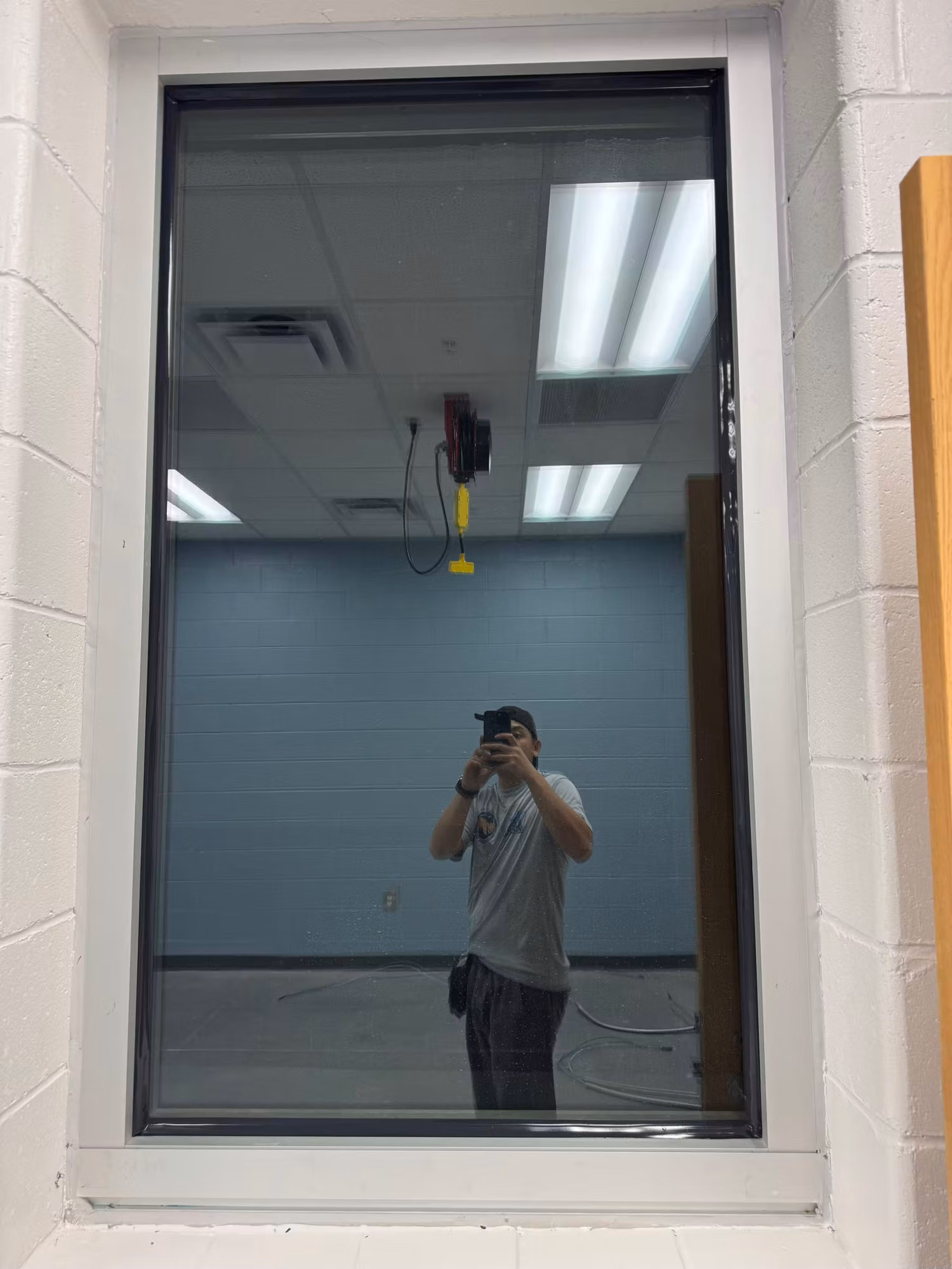 Tall interior block-wall window with darkened reflective film looking into a painted interior room.