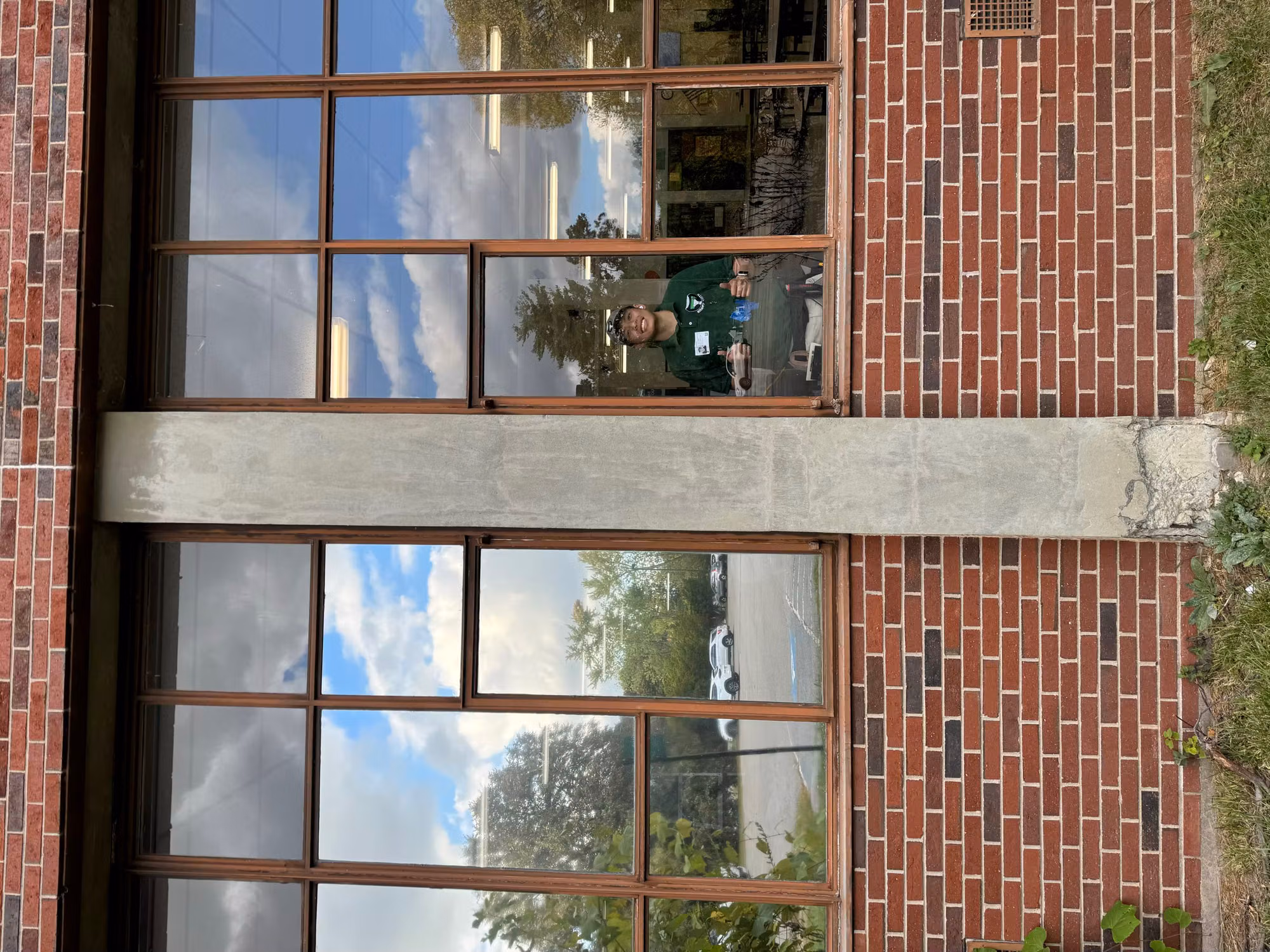 Two large brick-framed windows with reflective solar film and an installer visible through the glass inside.