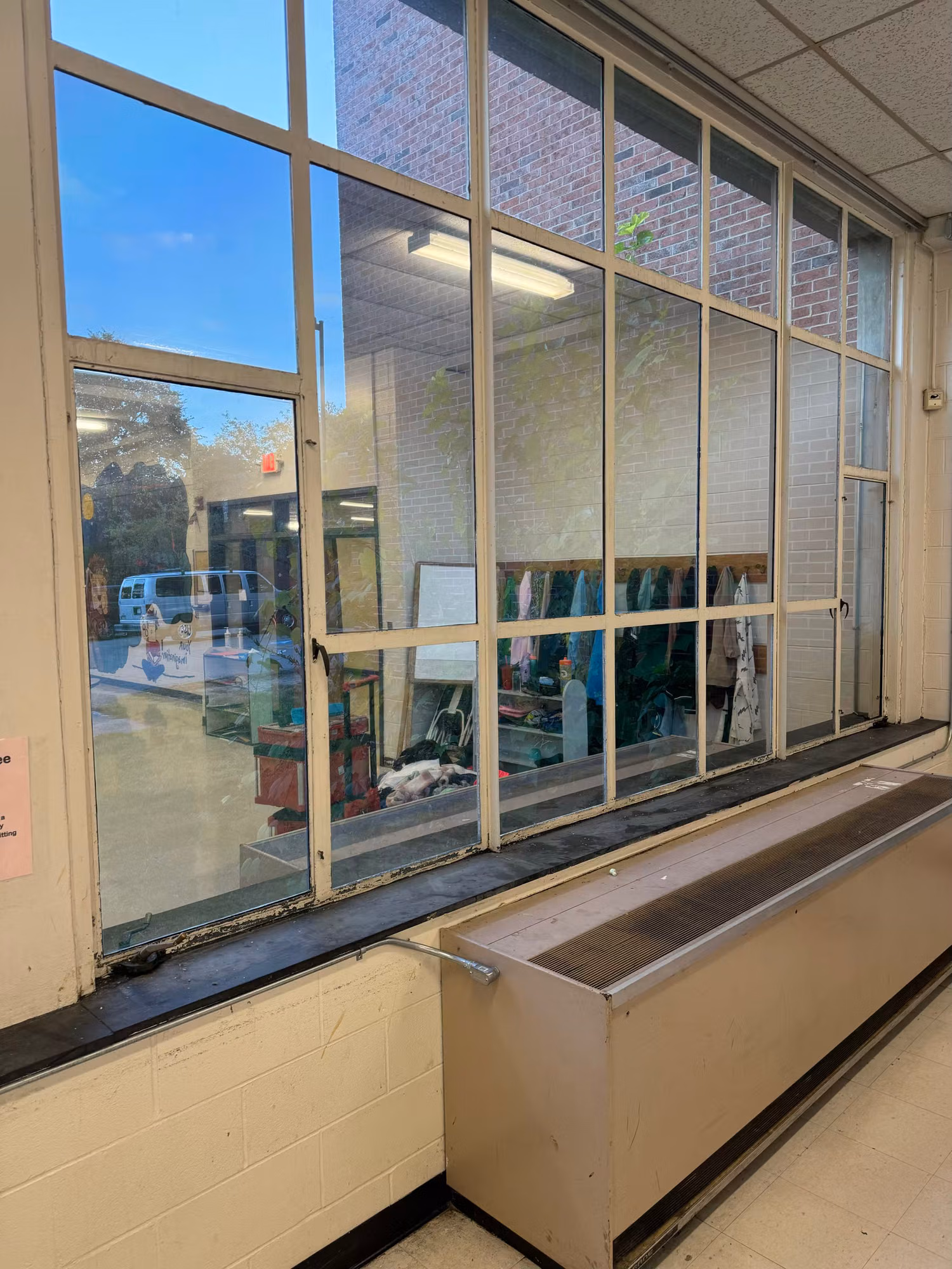 Large divided-light interior window wall with darkened solar film looking through to an adjacent school room.