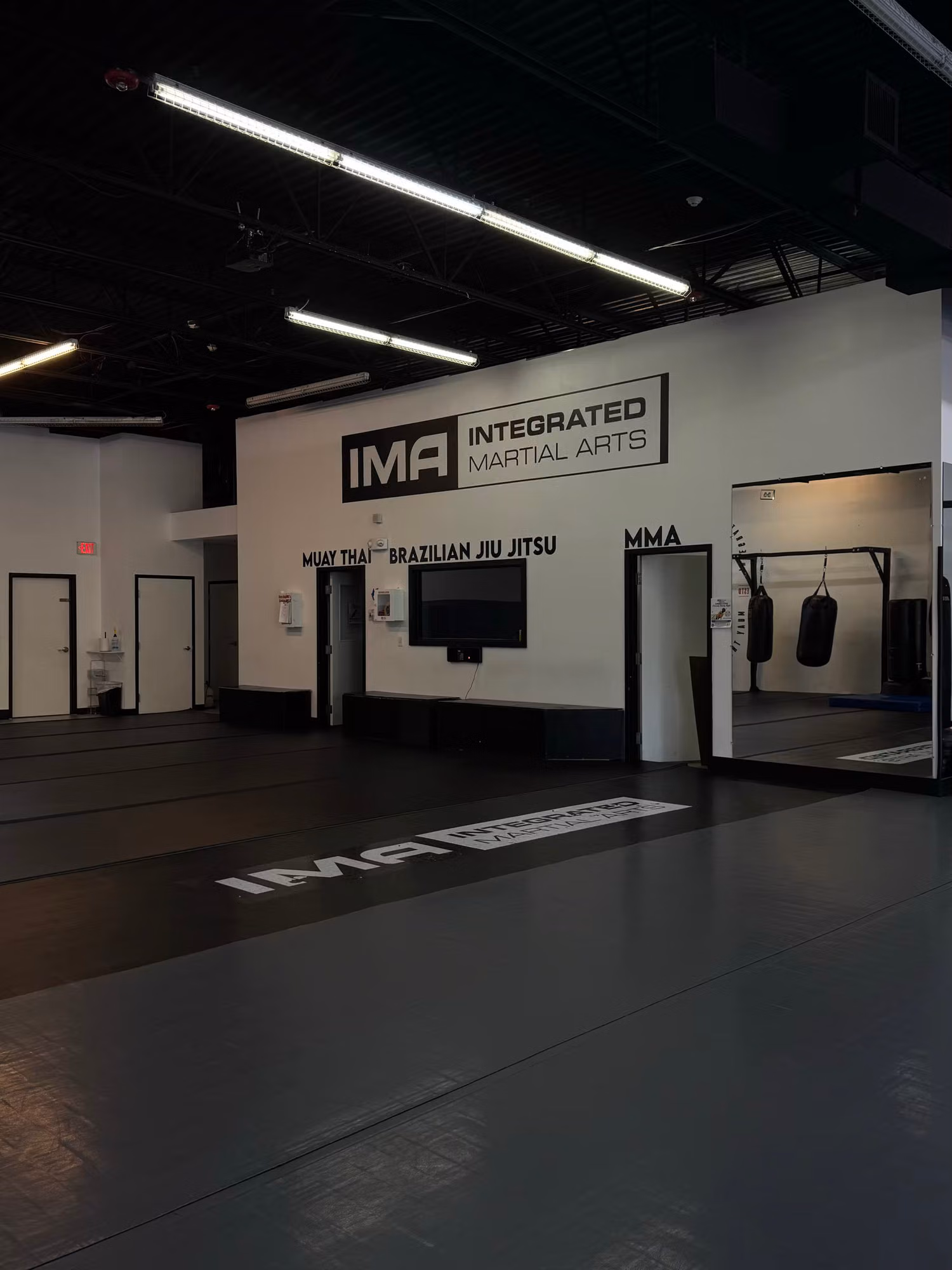 Gym interior with cut-vinyl wall lettering and logo applied above a doorway over matted training floors.