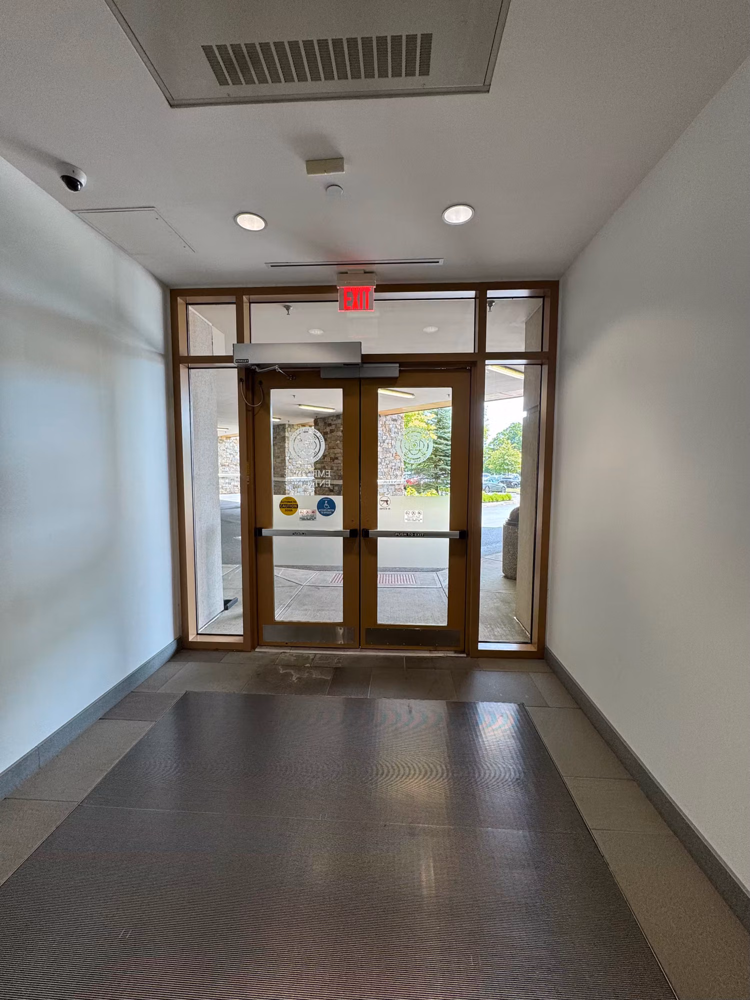 Interior entry vestibule with glass double doors, transom and sidelight windows leading to an exterior walkway.