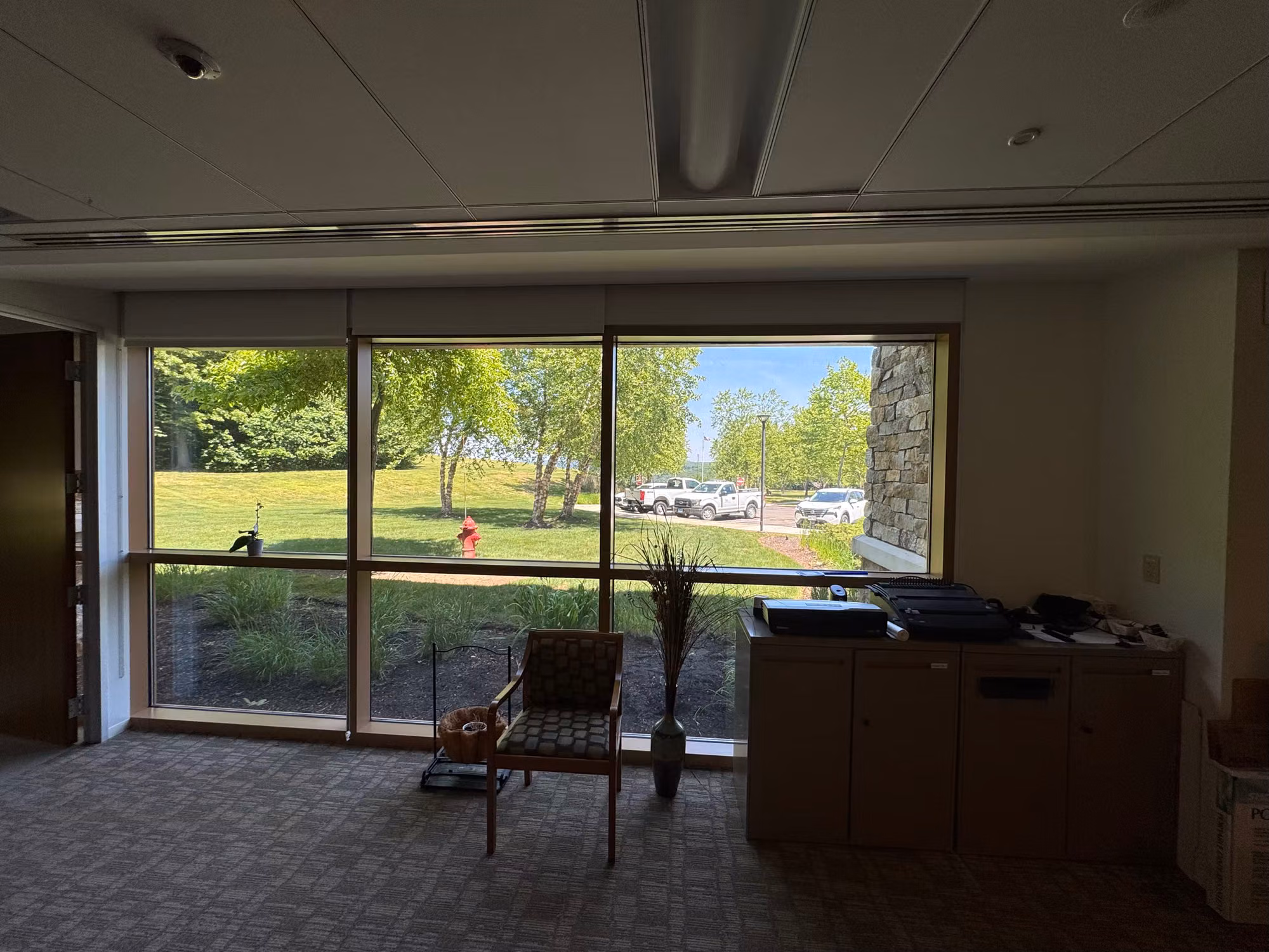 Office room with large picture windows overlooking a lawn, fitted with light-diffusing solar shades.