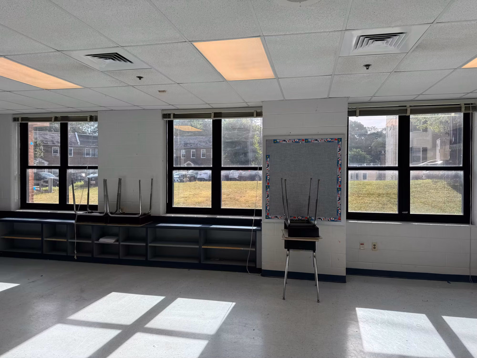 Empty classroom interior with multiple windows finished in darkened solar film reducing heat and glare.