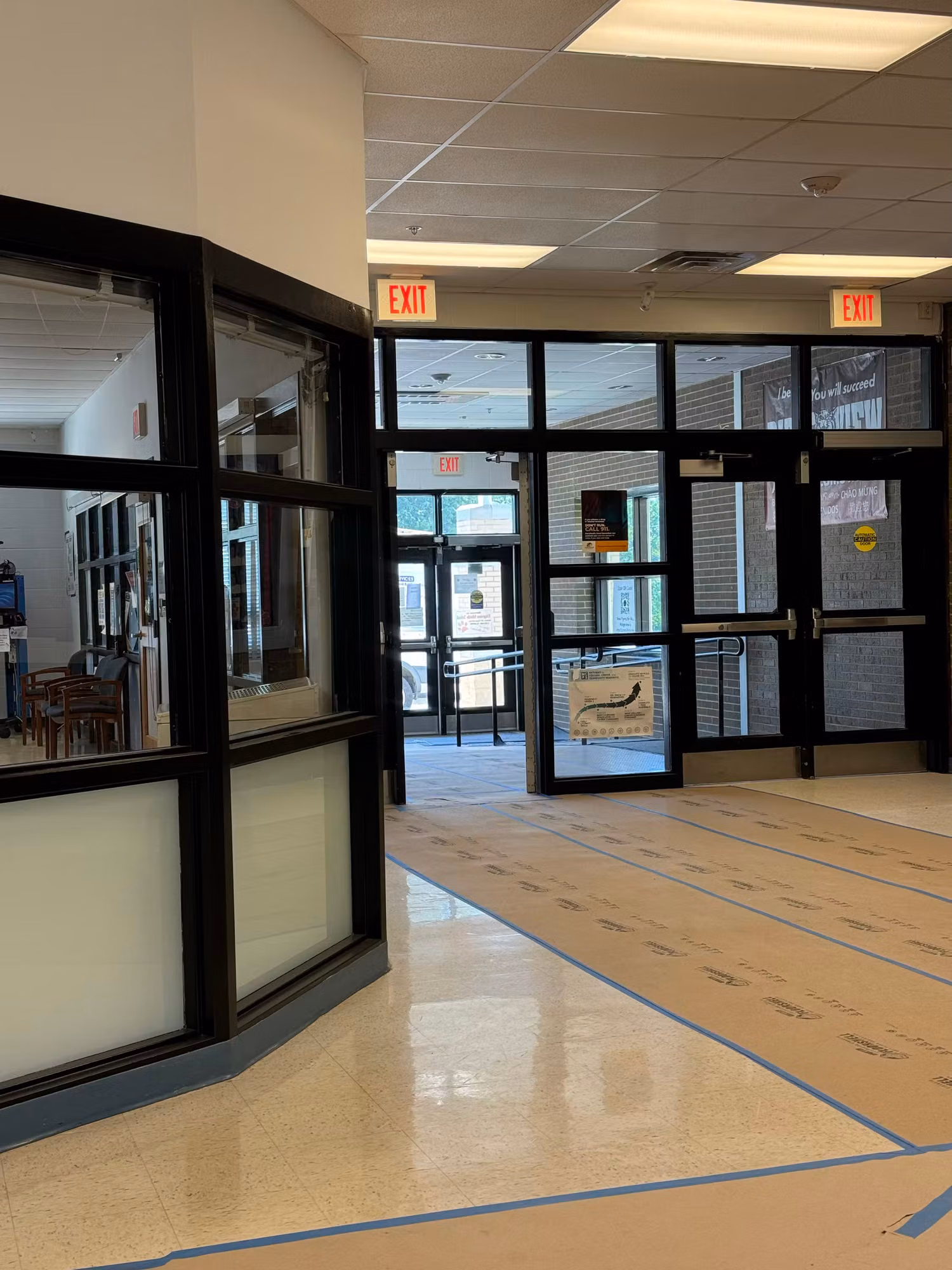 Interior lobby with black-framed glass entry doors and a curved partition wall finished with a frosted privacy band.