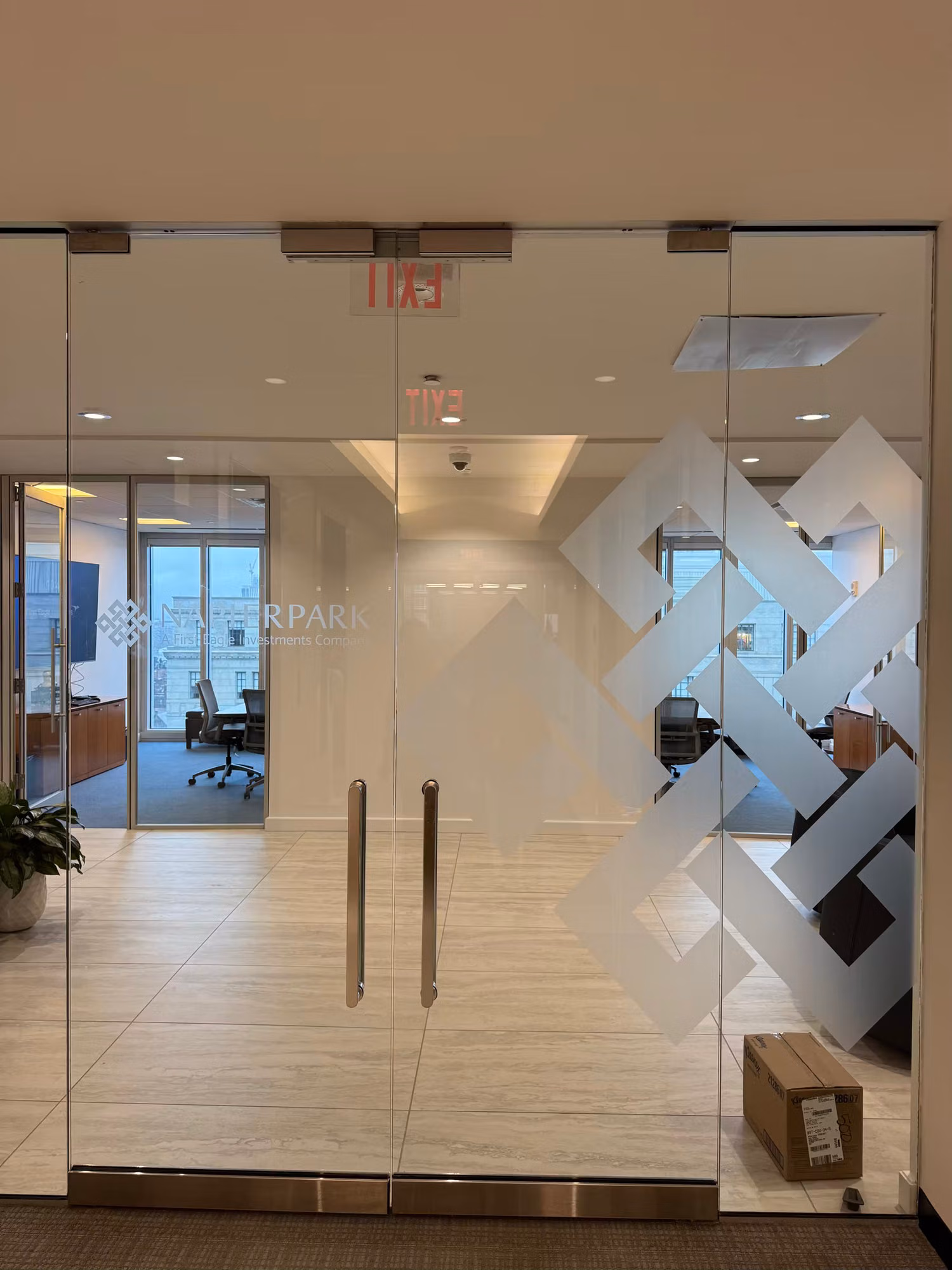 Glass office entry doors with a frosted geometric pattern and etched logo lettering on the partition.