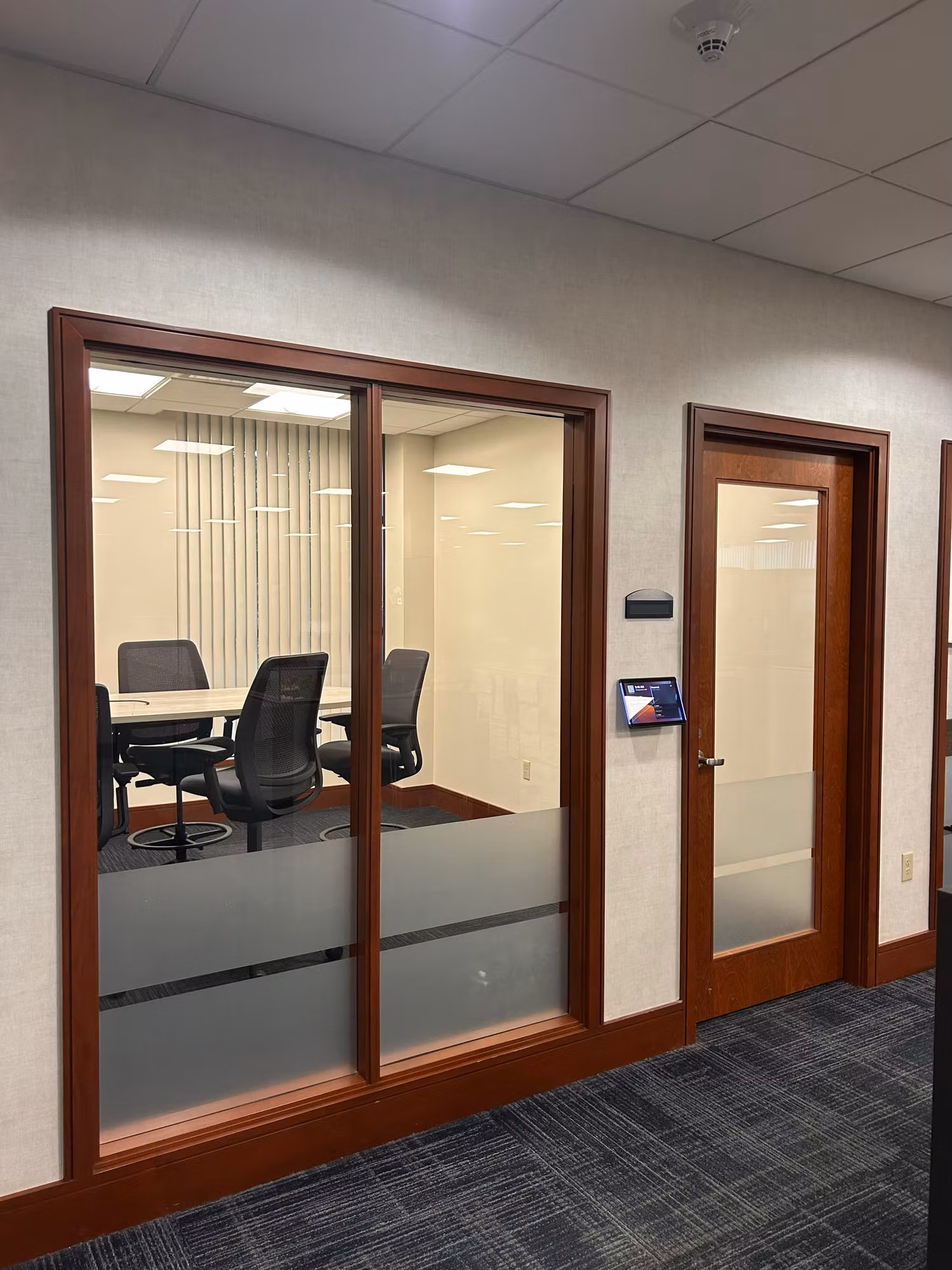 Wood-framed conference room glass doors with a frosted privacy band along the lower glass.