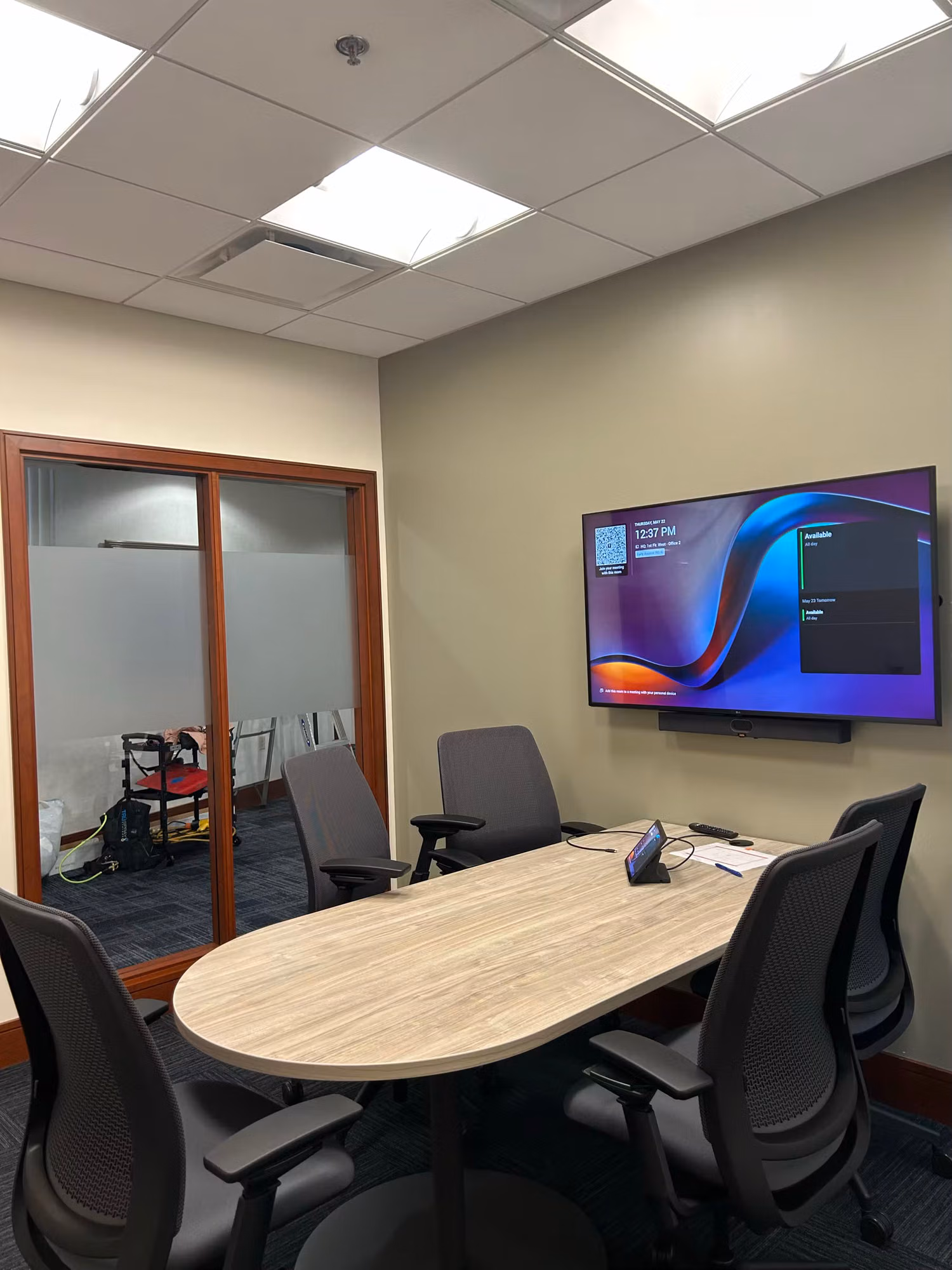 Meeting room with a wall display and glass partition double doors carrying a frosted privacy band along the side wall.