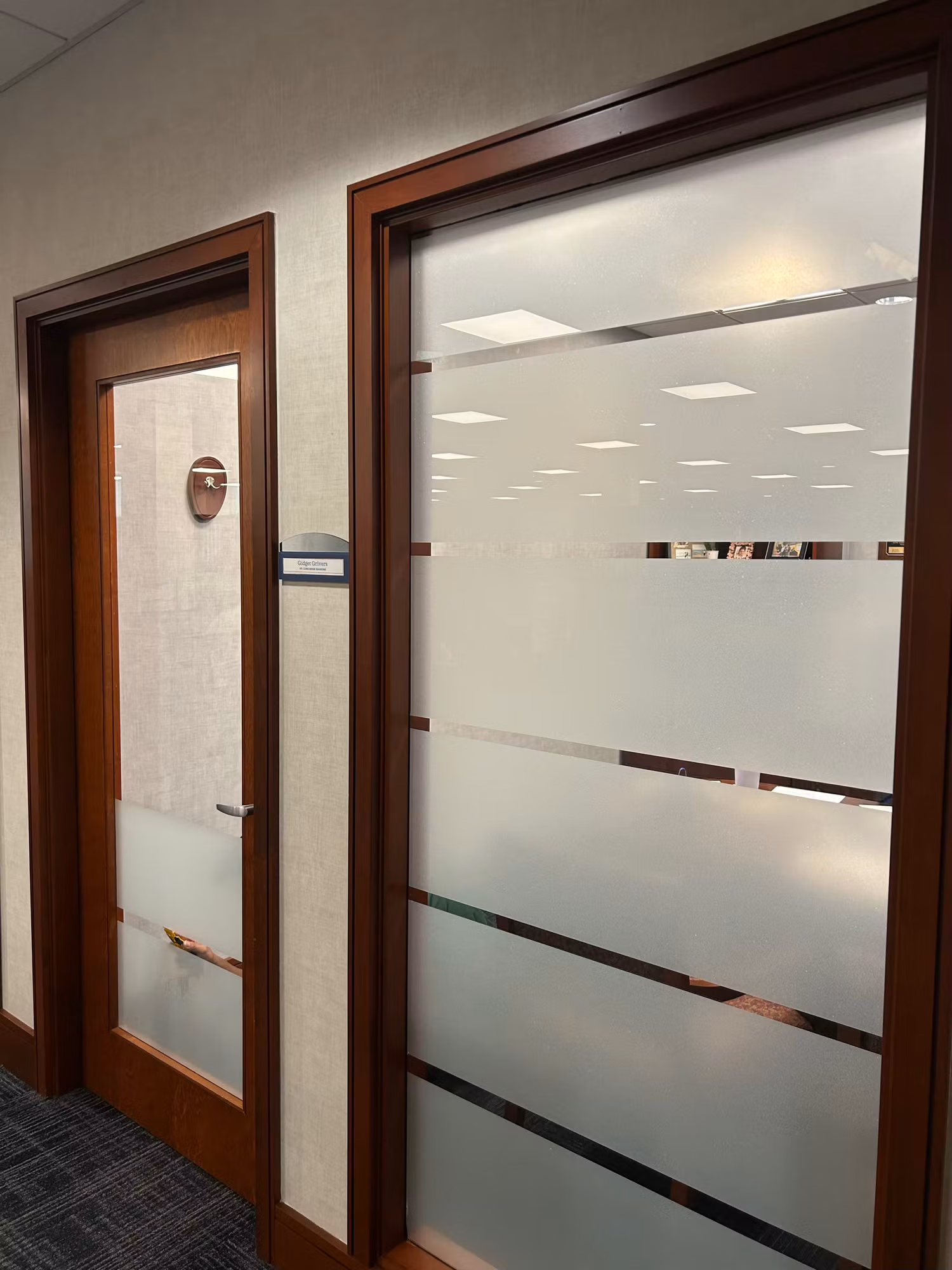 Office door and glass partition finished with graduated horizontal frosted stripes for a layered privacy pattern.