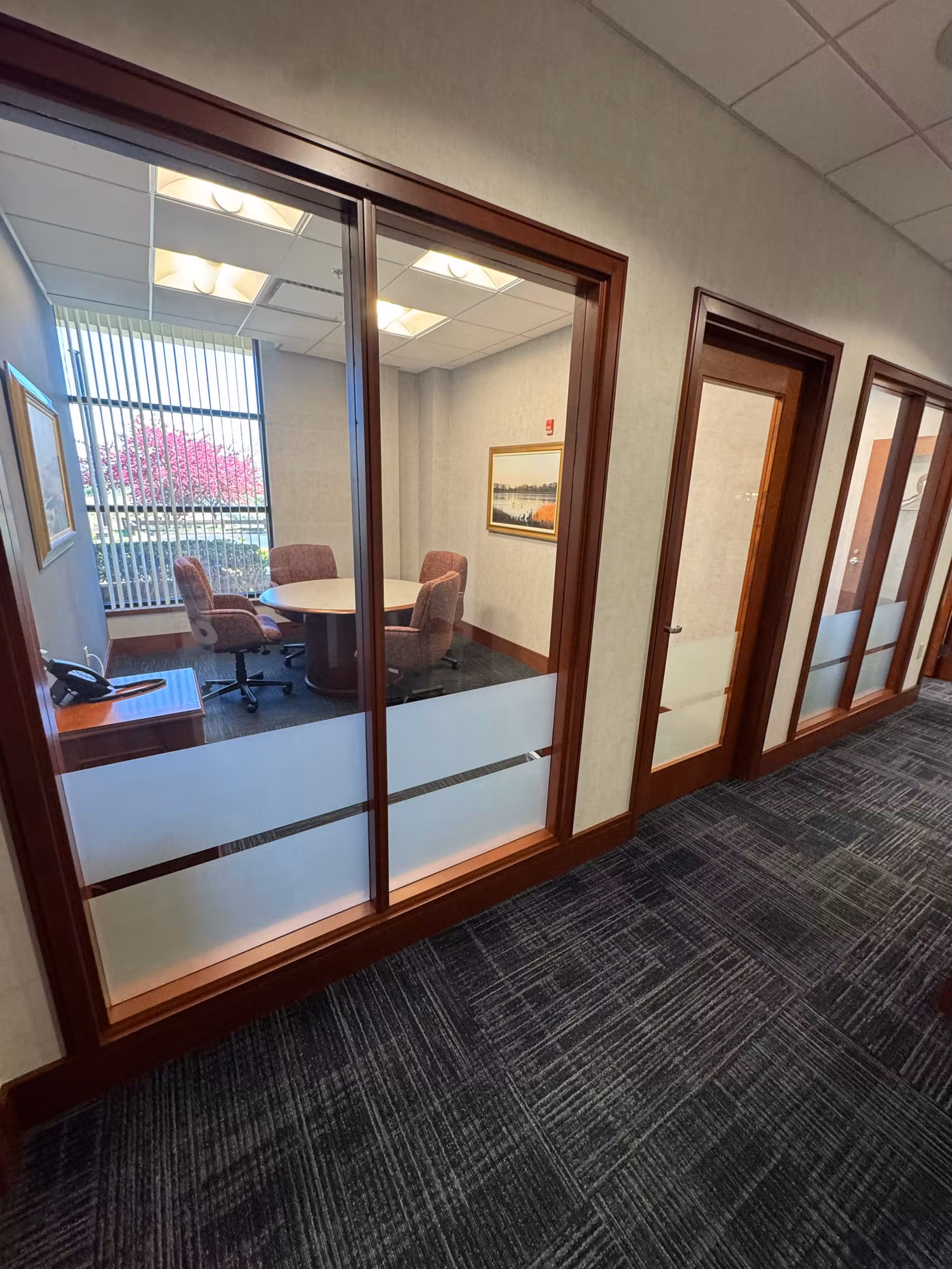 Wood-framed glass office front fronting a conference room, with frosted privacy film along the lower glass panels.