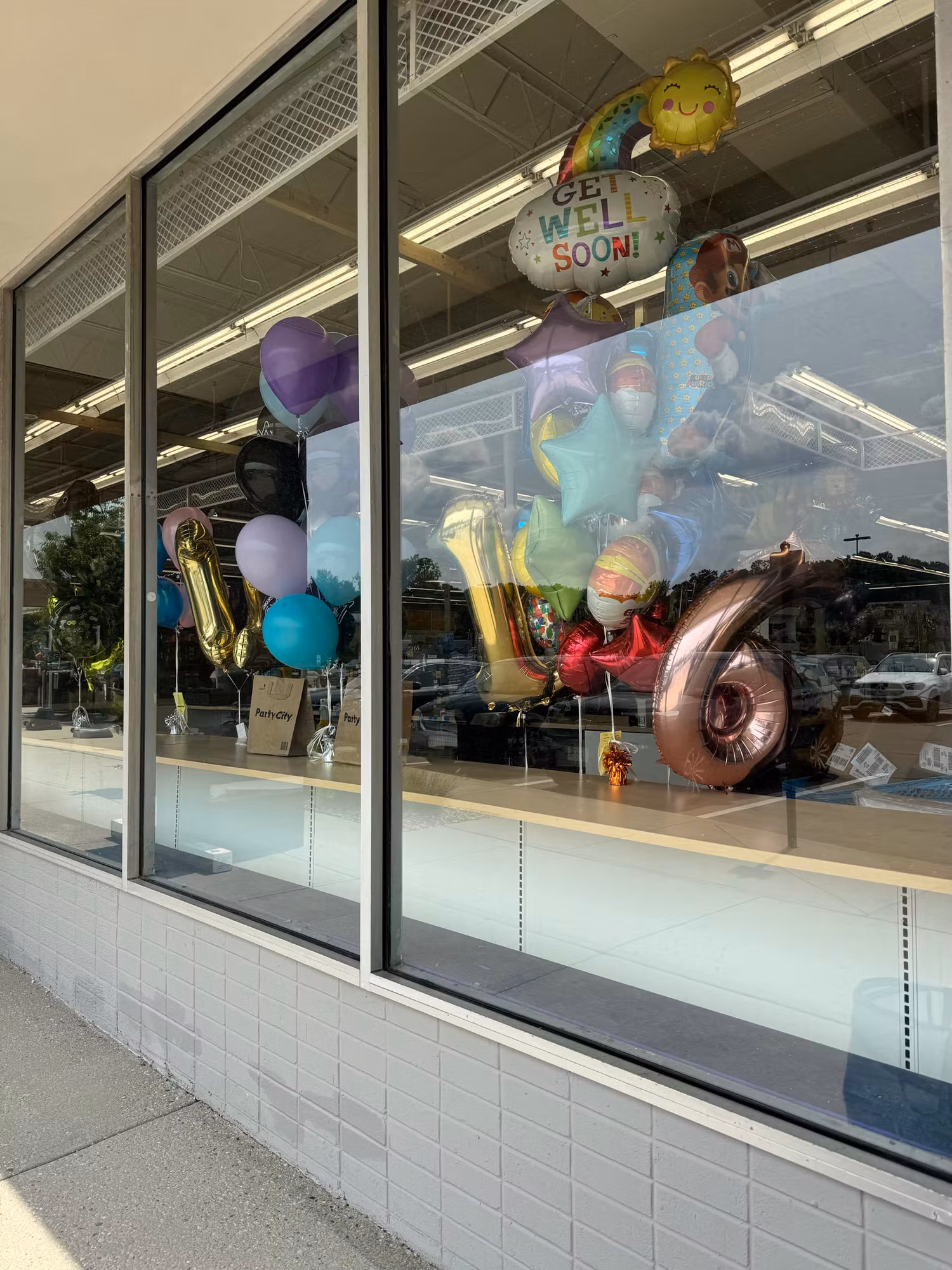 Storefront glass panels with tinted lower sections and colorful balloons arranged behind the windows.