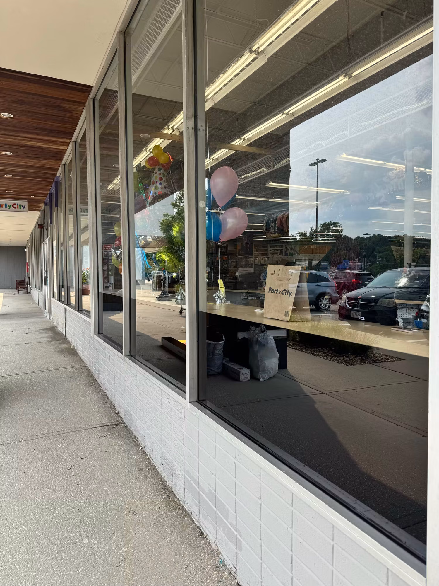 Storefront windows with darkened lower glass panels reflecting the parking lot above a white brick base.