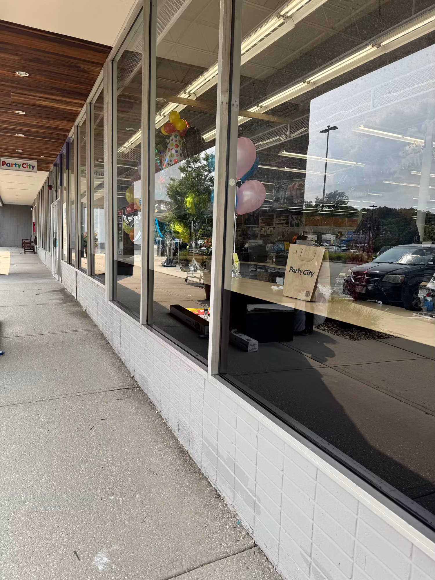 Storefront windows with darkened reflective lower glass running along the sidewalk of a single-story retail building.