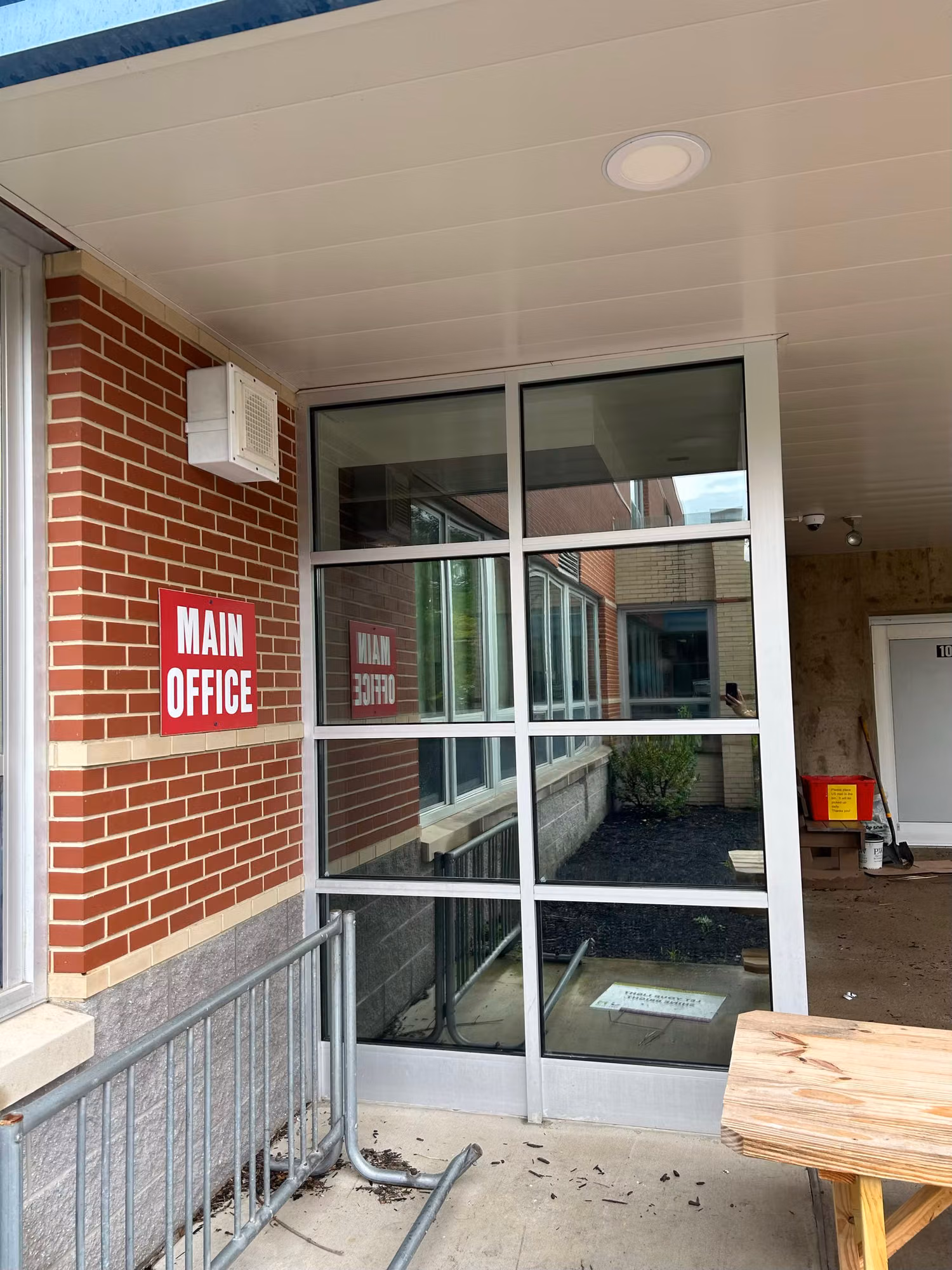 Glass storefront entry doors and sidelights at a building main office, tinted under a covered walkway entrance.